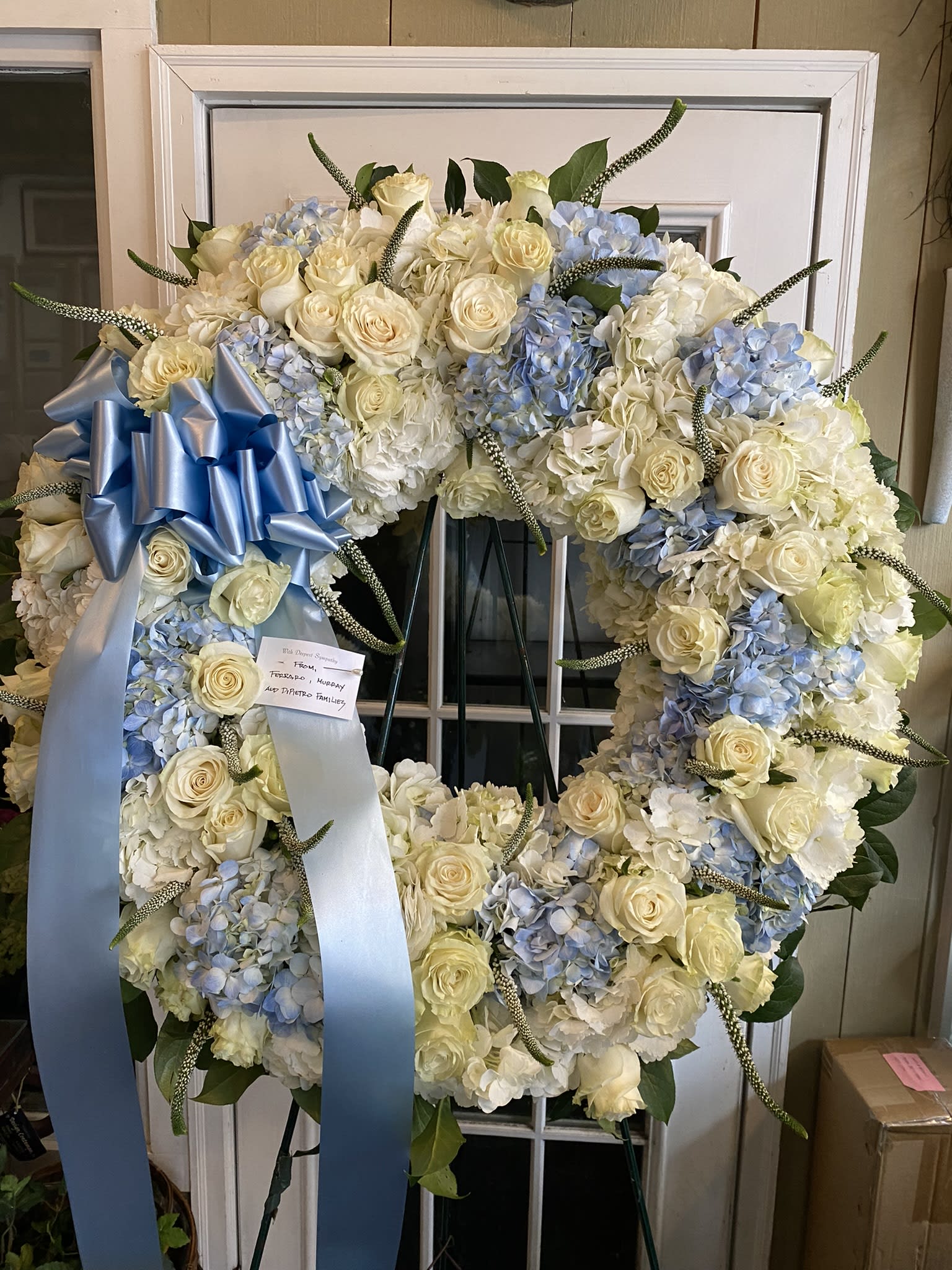 Large white and pale blue floral wreath with a blue ribbon bow