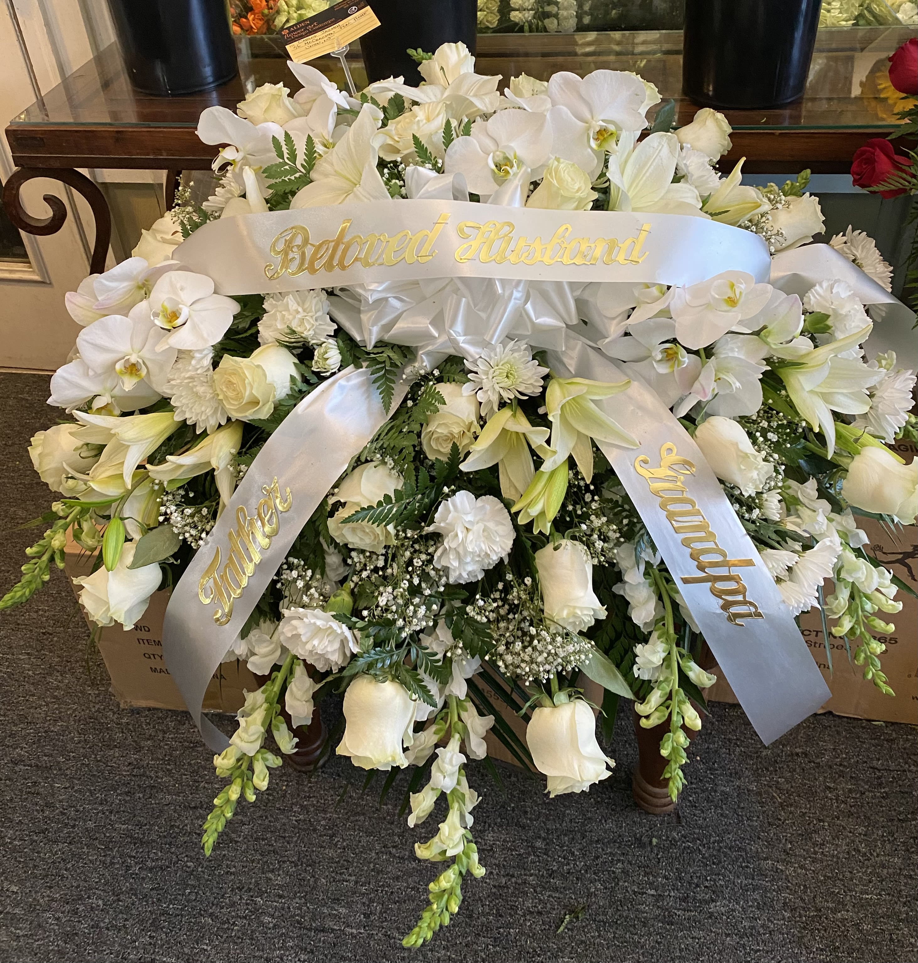 White funeral spray with ribbons reading Beloved Husband and Father