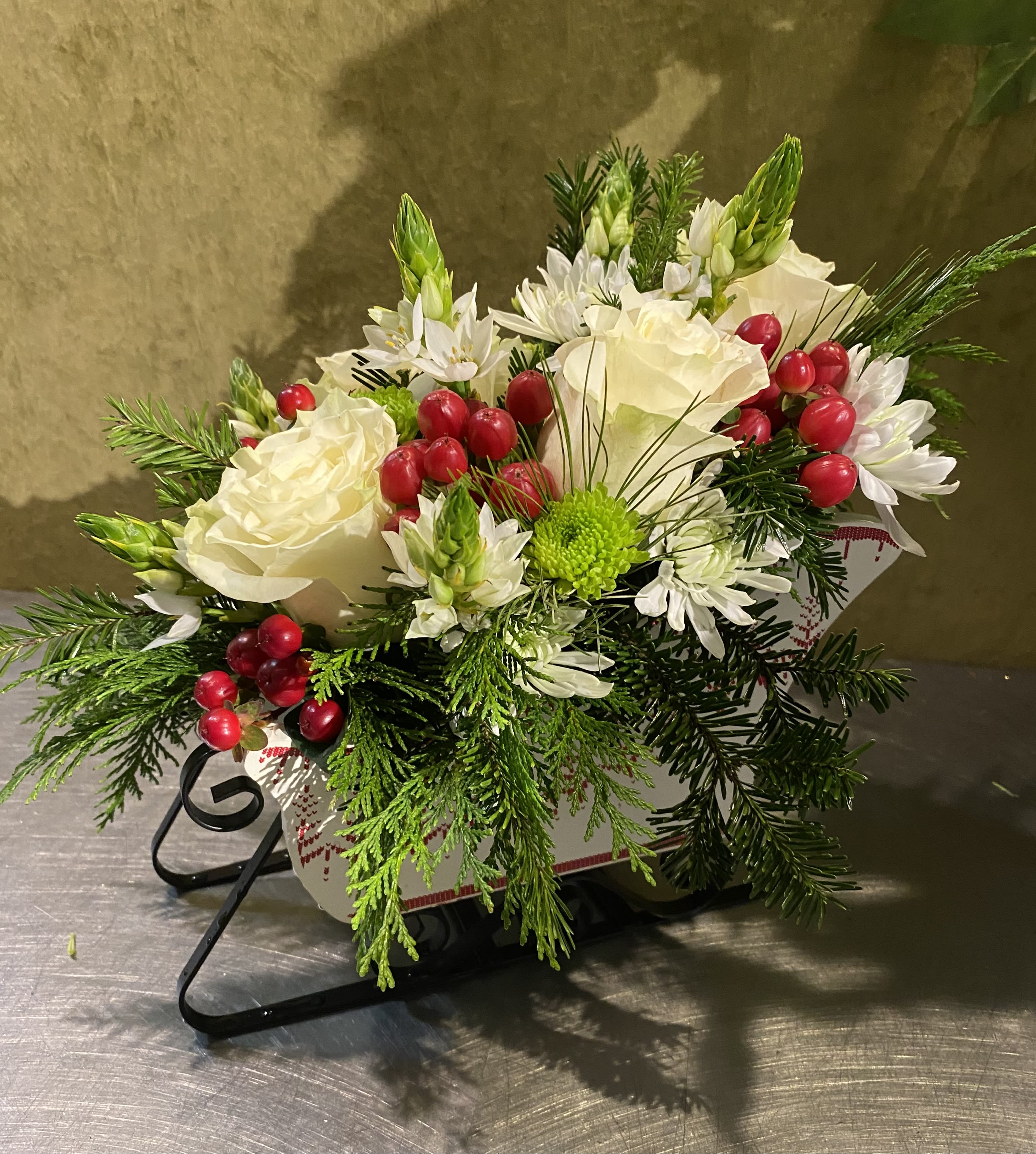 White floral arrangement with red berries in a decorative container