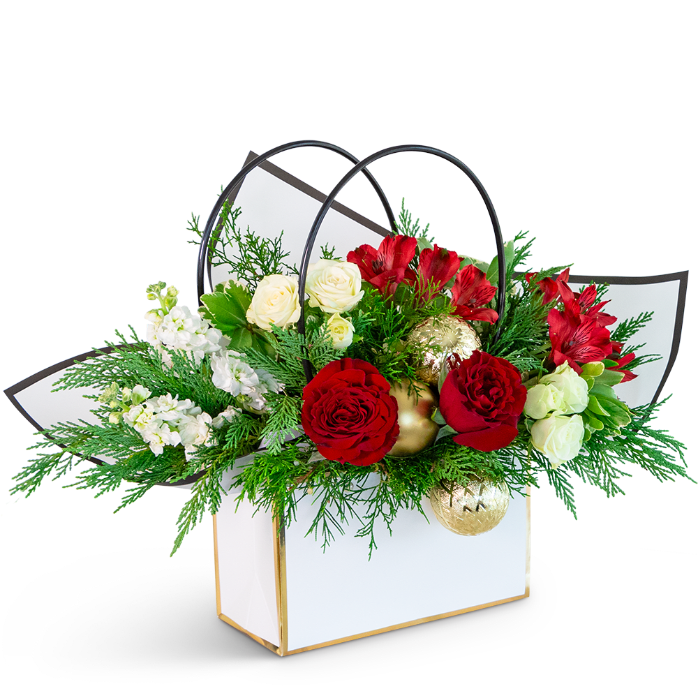 Holiday Cheer Tote - Our Holiday Cheer Tote is a festive mix of reds, whites, and greens in a vibrant flower arrangement destined to spread joy and merriment. Our commitment to quality guarantees a stunning display, with potential variations from the flowers depicted. Presented in a chic Flower gift tote bag, this captivating arrangement will not only bring a touch of holiday spirit to the recipient's day but also provide easy transport and delivery for a thoughtful and convenient gift-giving experience.