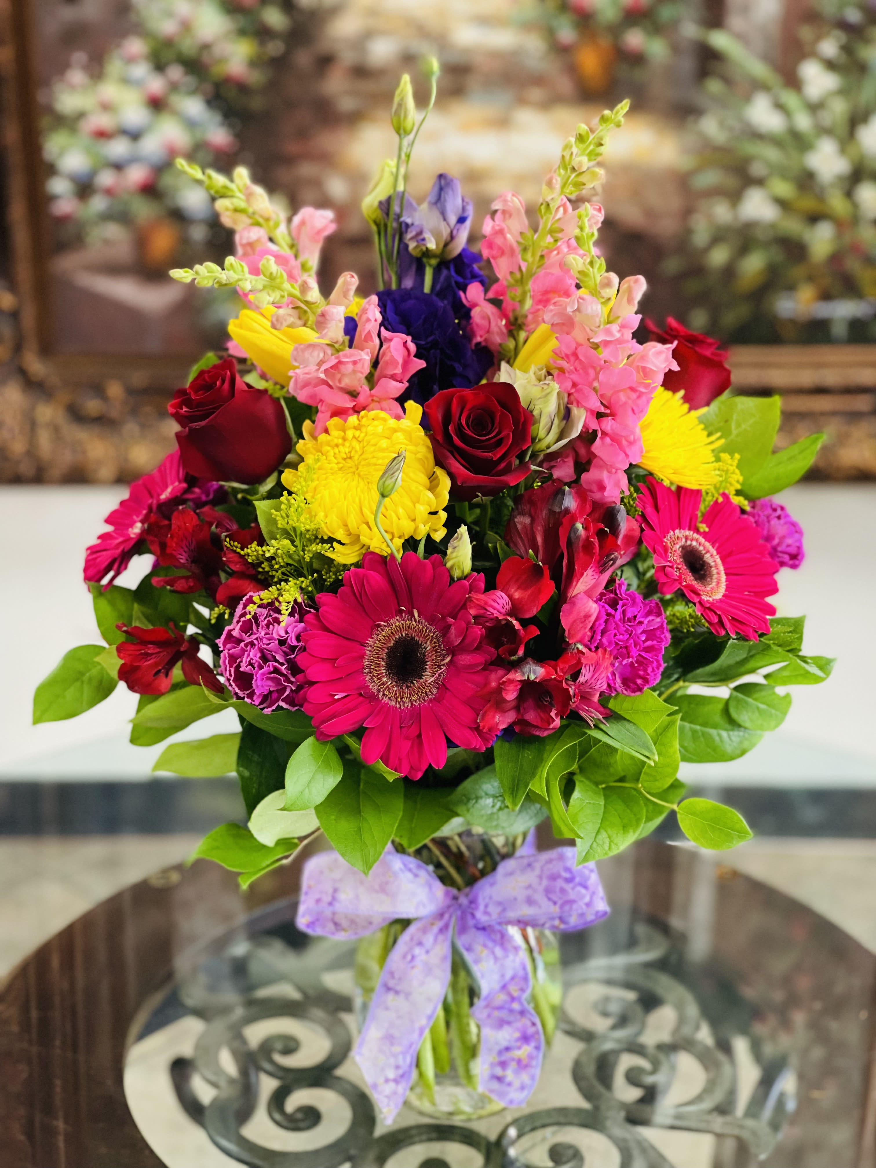 Bright mixed bouquet with roses, gerbera daisies, and snapdragons in a glass vase