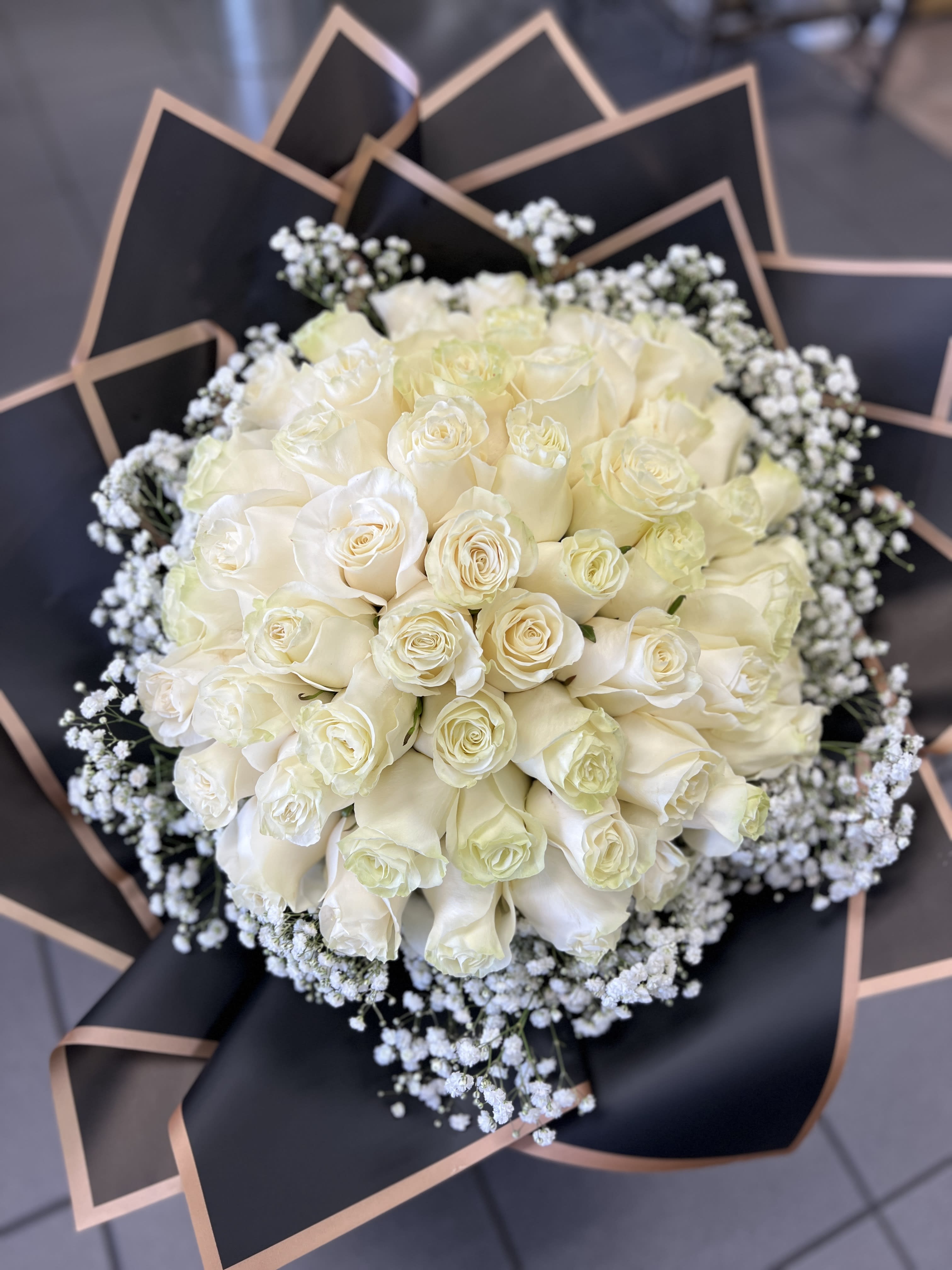 Bouquet of white roses with baby's breath in black wrap