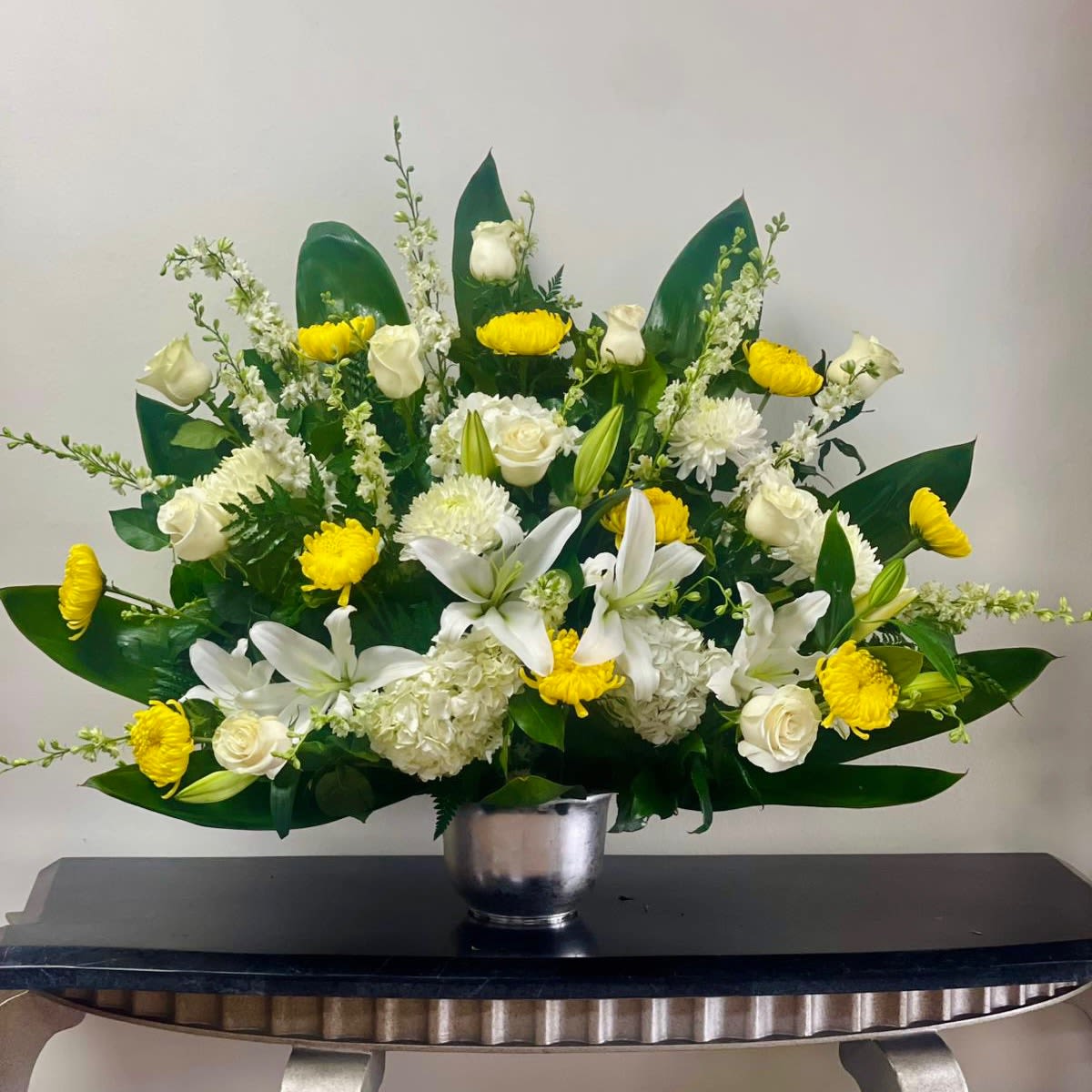 White lilies and roses with yellow mums in a silver vase