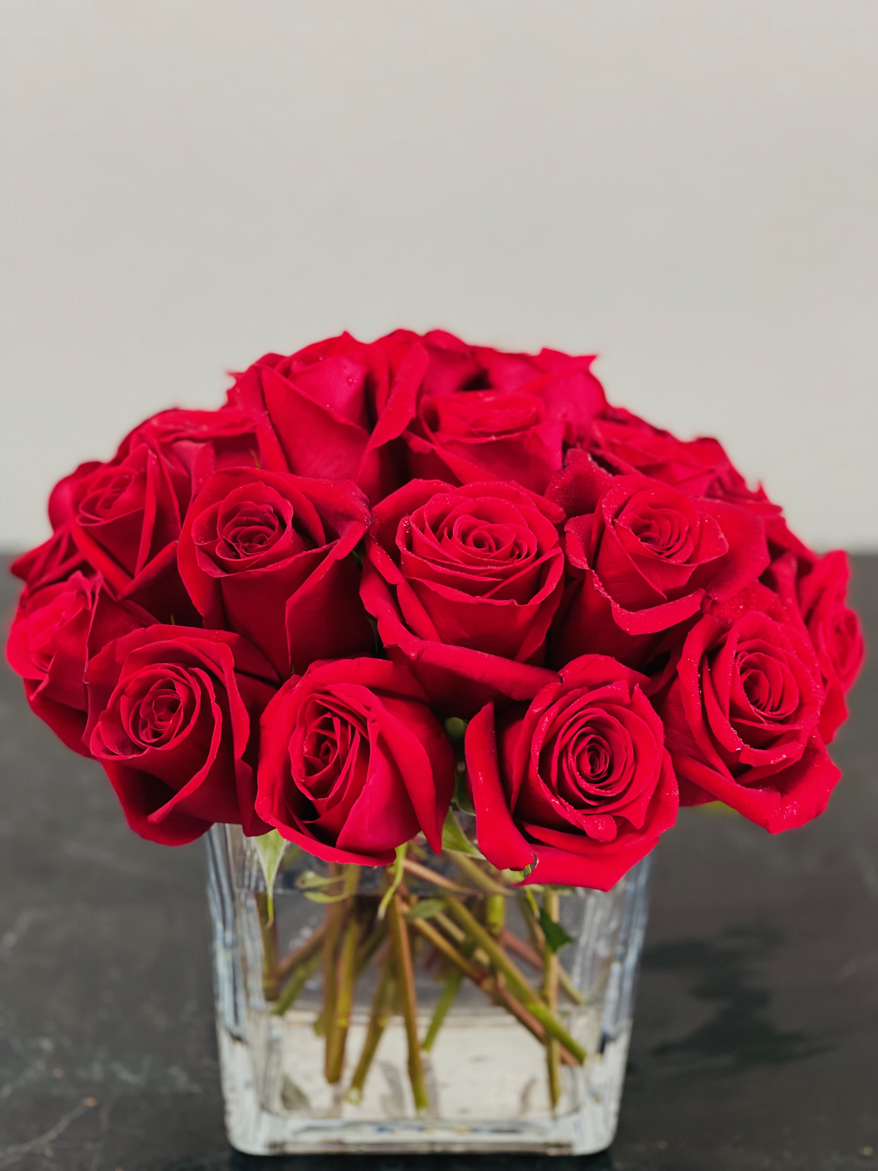 Red roses arranged in a clear glass vase