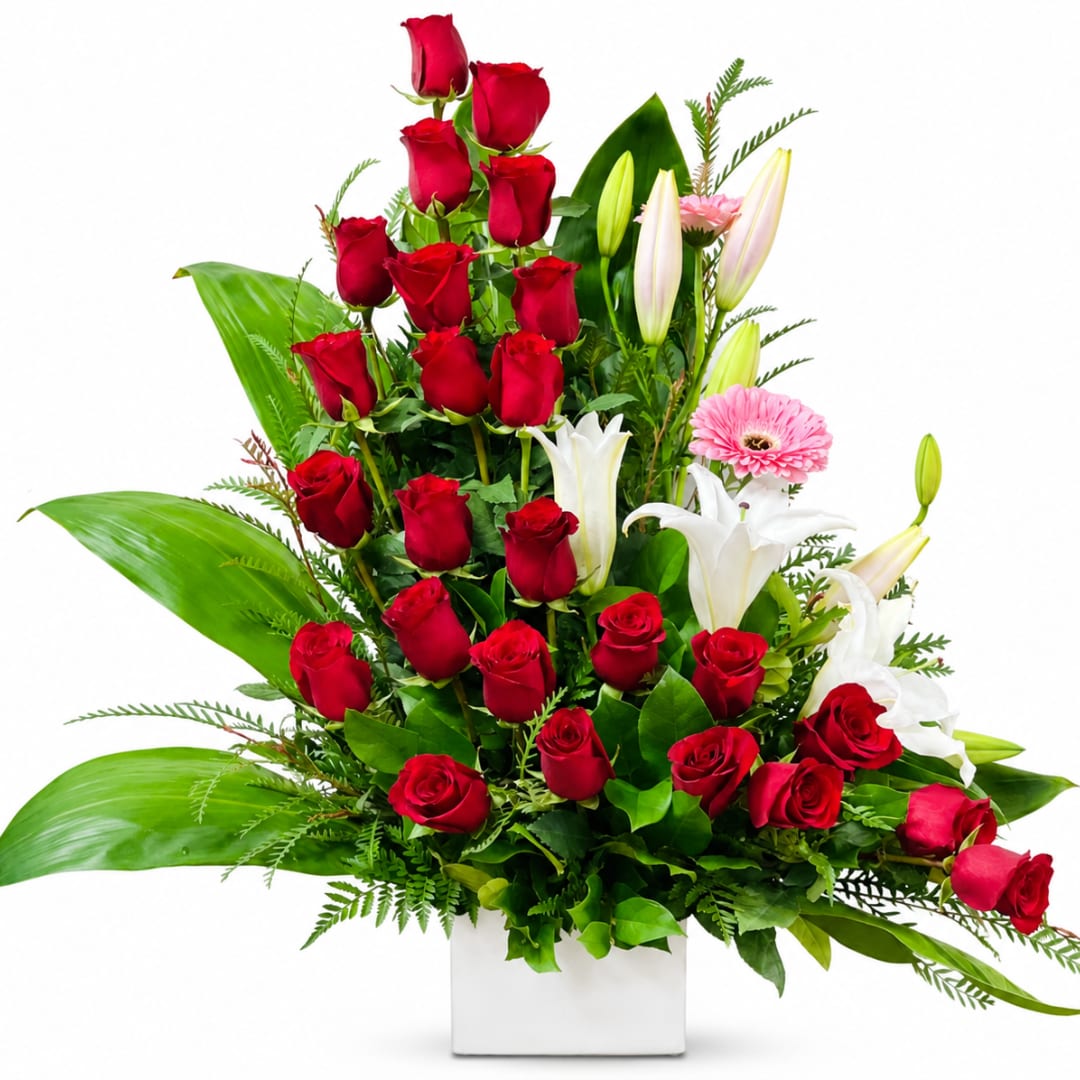 Tall arrangement of red roses, white lilies, and pink gerbera daisies in a white vase