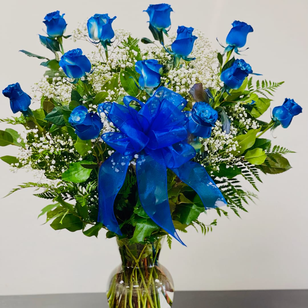 Blue roses with baby's breath in a clear glass vase, tied with a blue bow