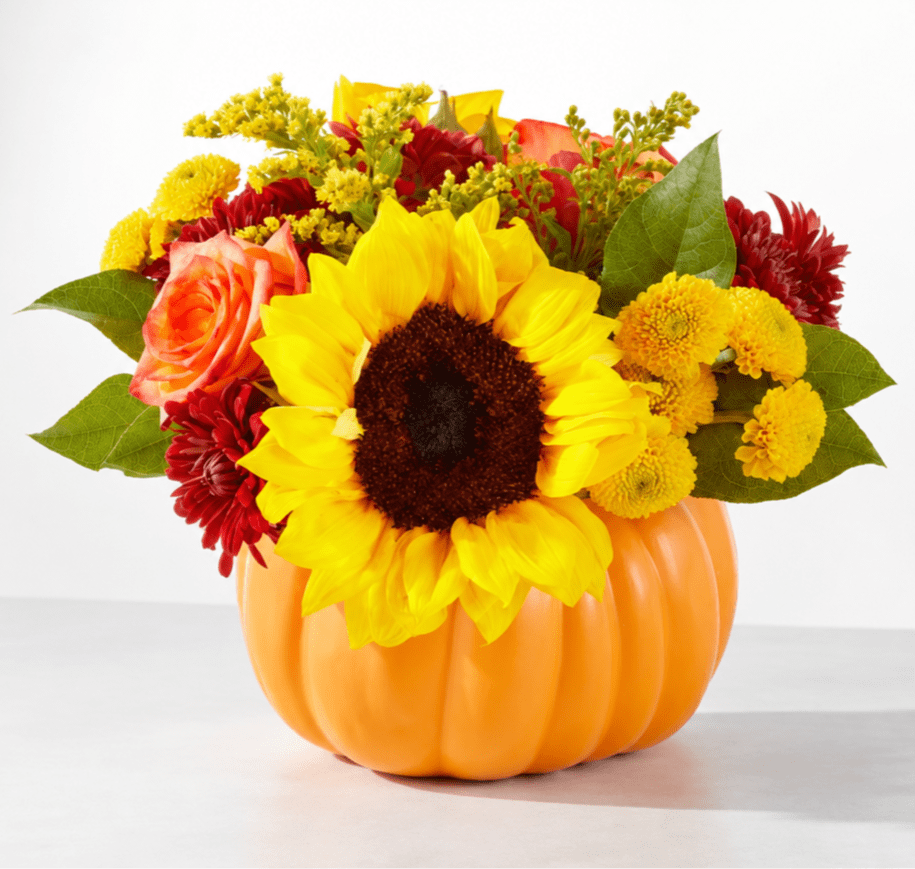 Sunflower and mixed flower arrangement in an orange pumpkin container