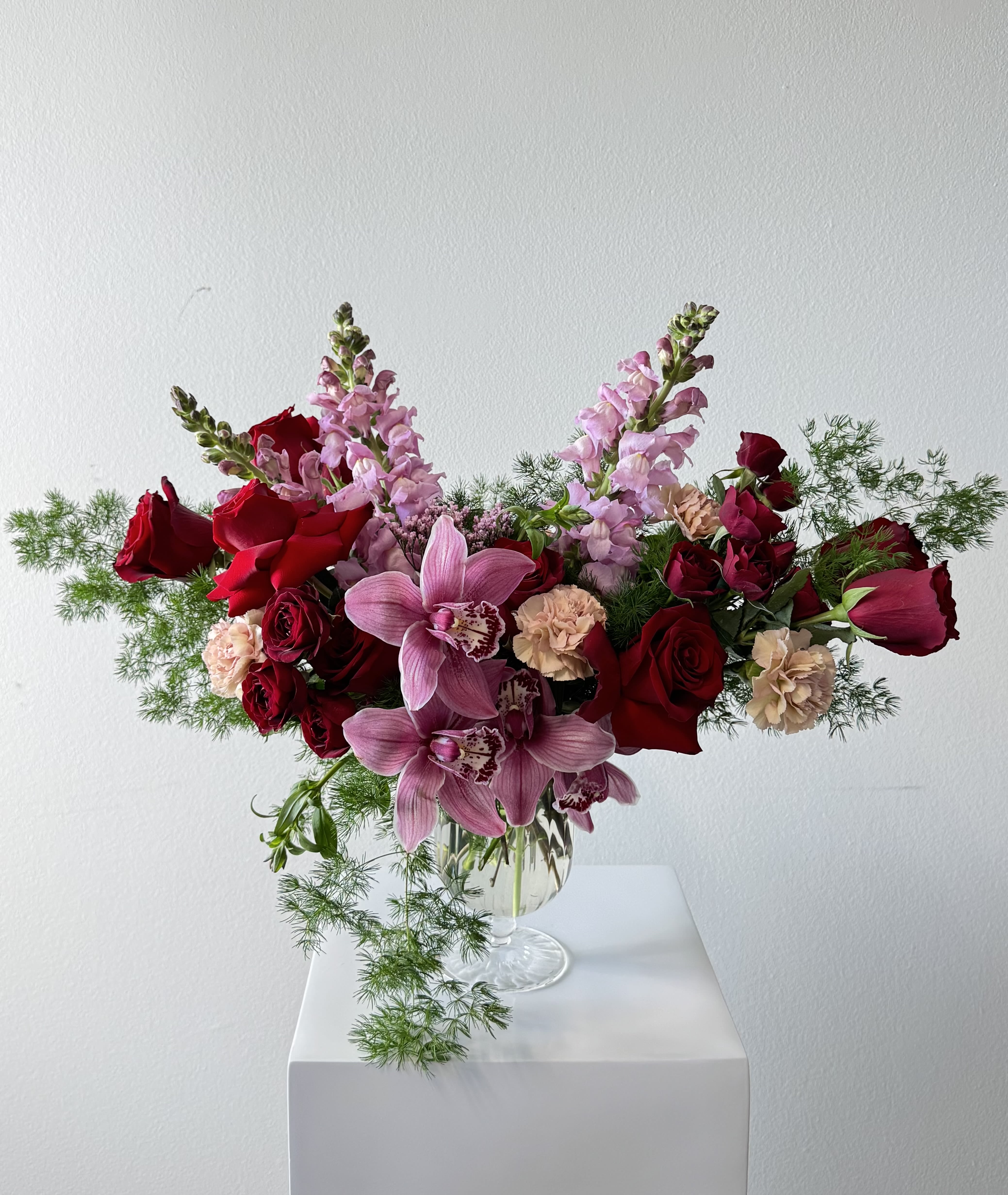 Pink orchids and red roses arranged in a clear glass vase