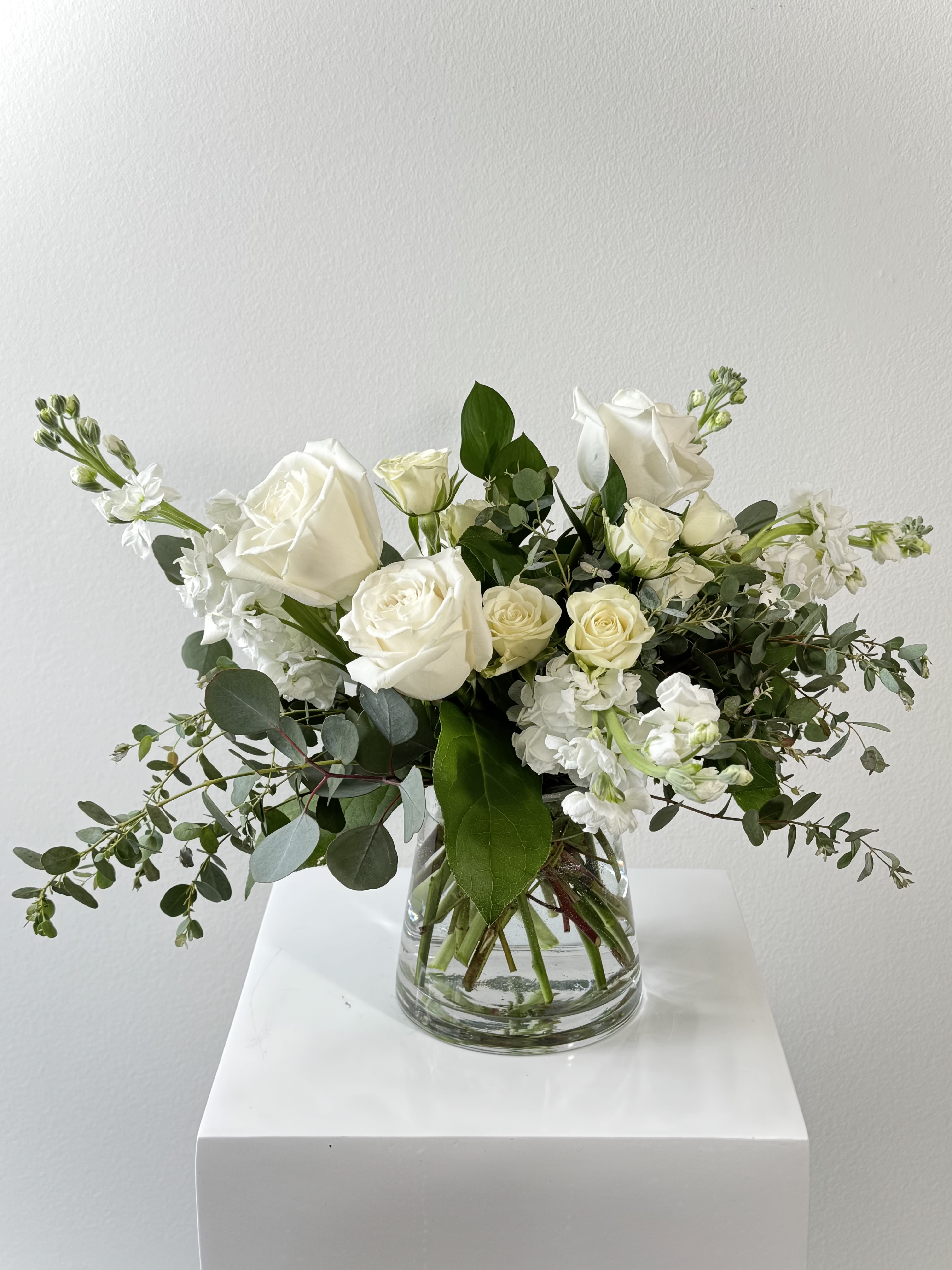 White roses and white stock in a clear glass vase