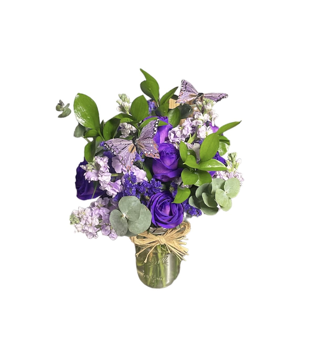 Purple roses and lavender flowers in a glass vase with butterfly picks