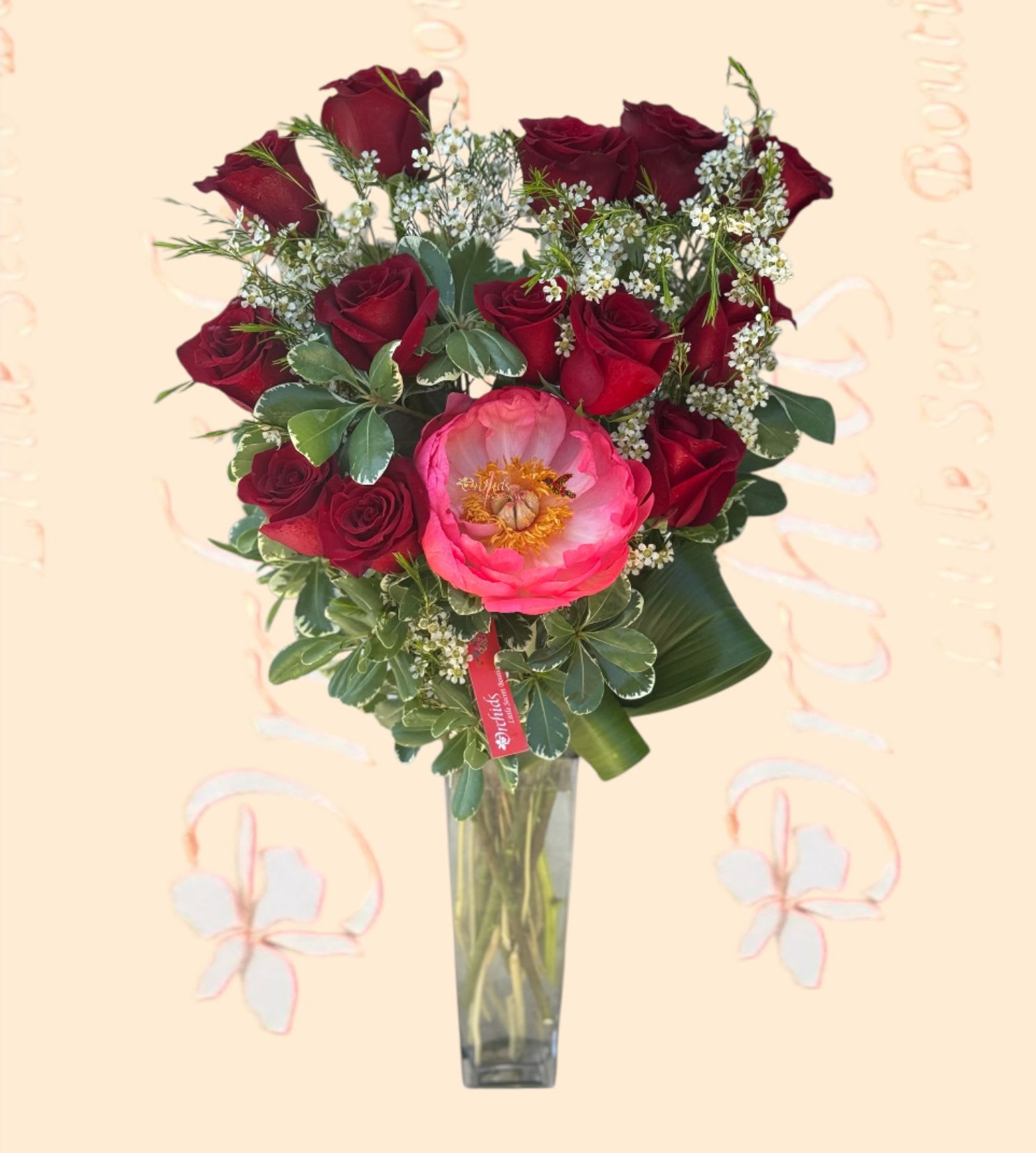 Bouquet of red roses and a pink peony in a tall glass vase