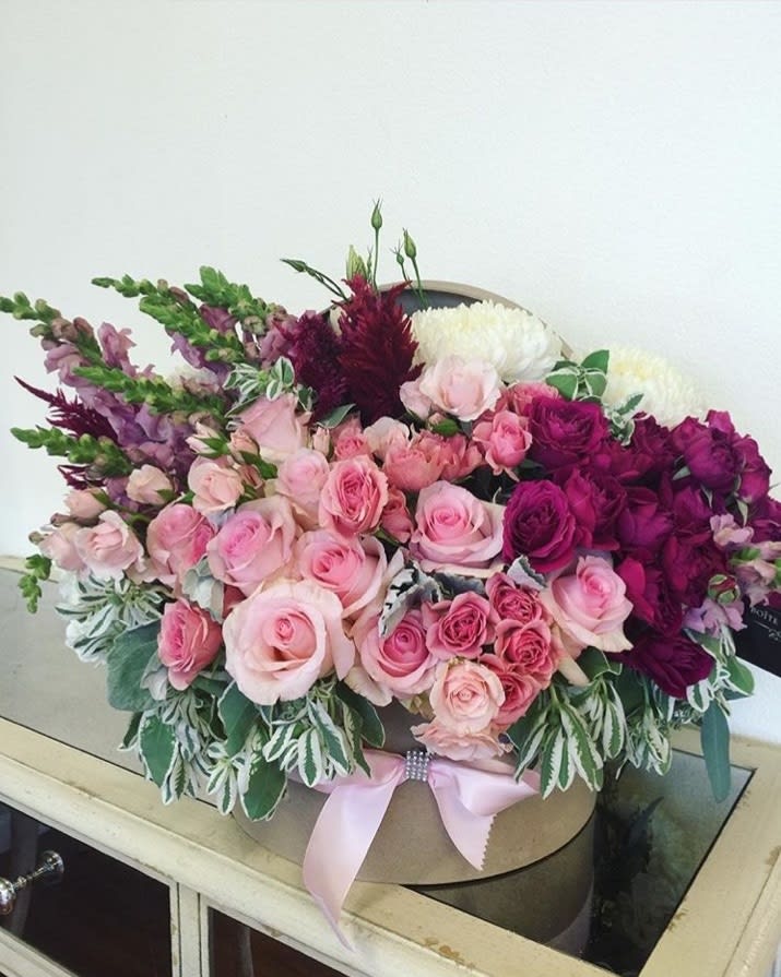 Pink and purple rose bouquet in a round box with a ribbon
