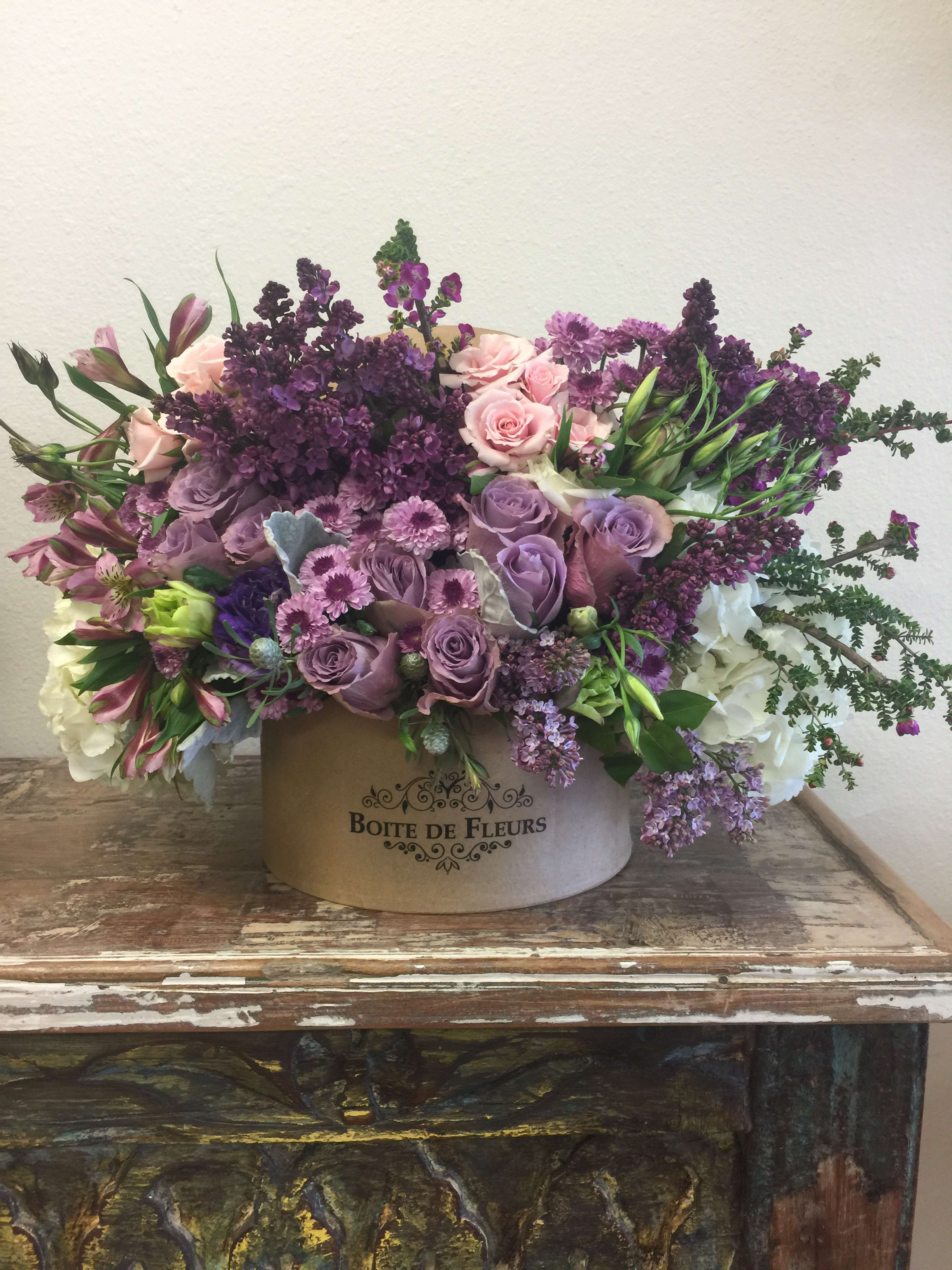 Lavender and pink floral arrangement in a round box