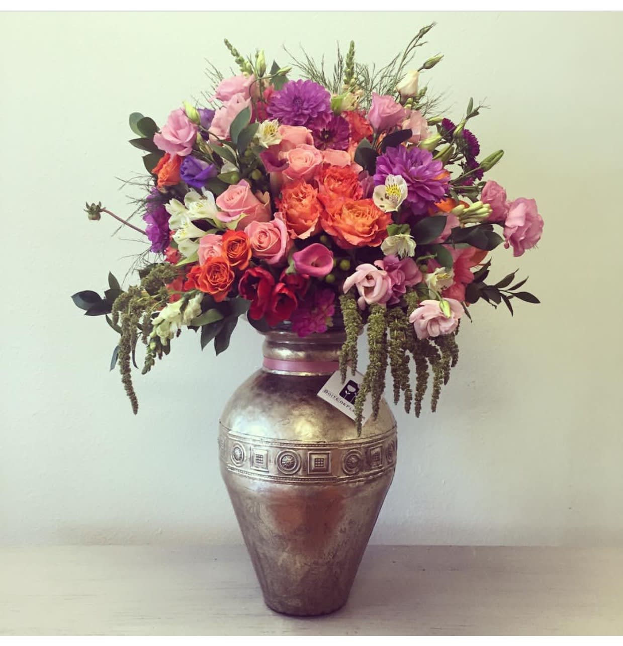 Mixed pink, purple, and orange flowers arranged in a metallic vase