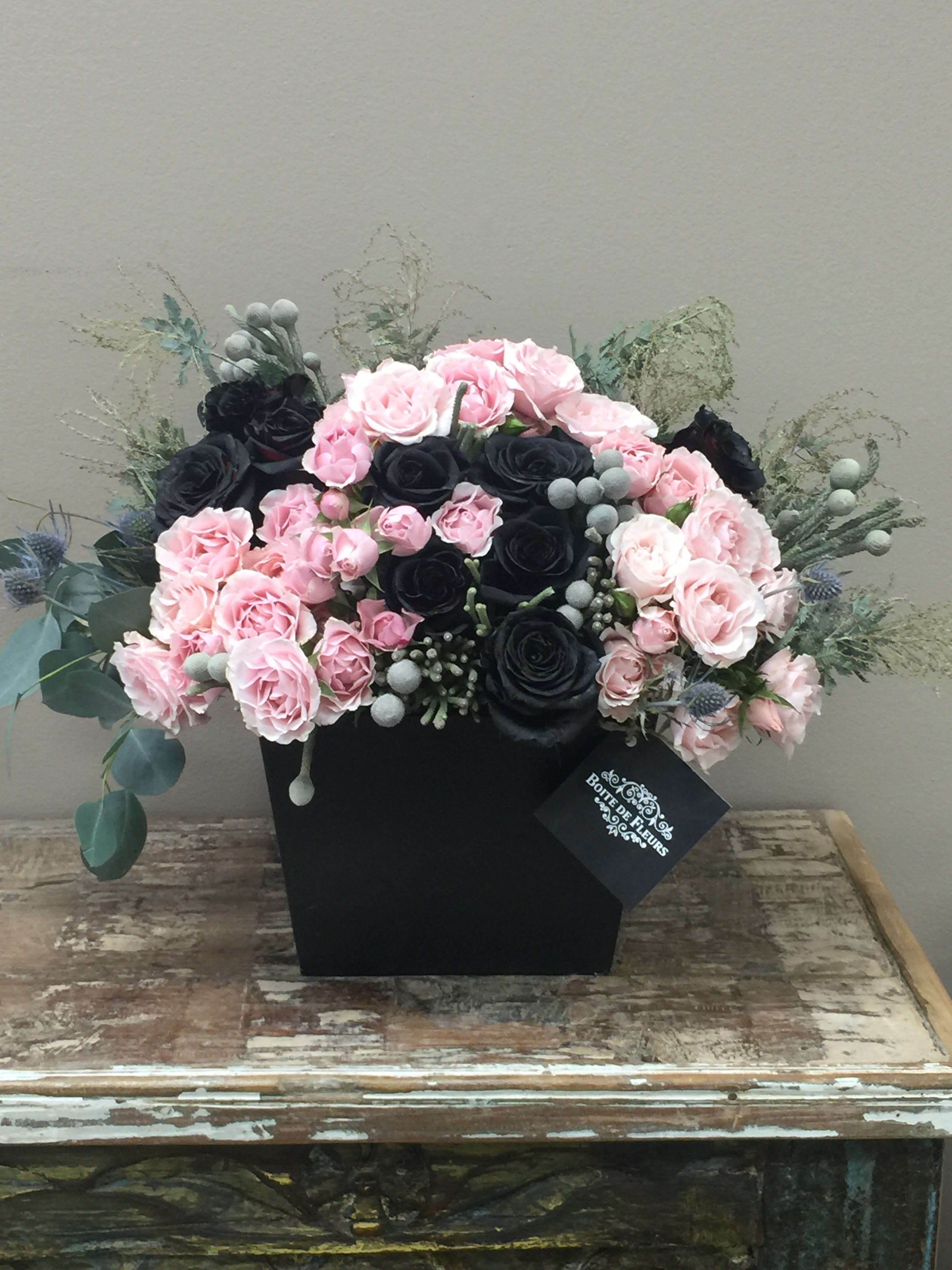 Pink and black rose arrangement in a black box