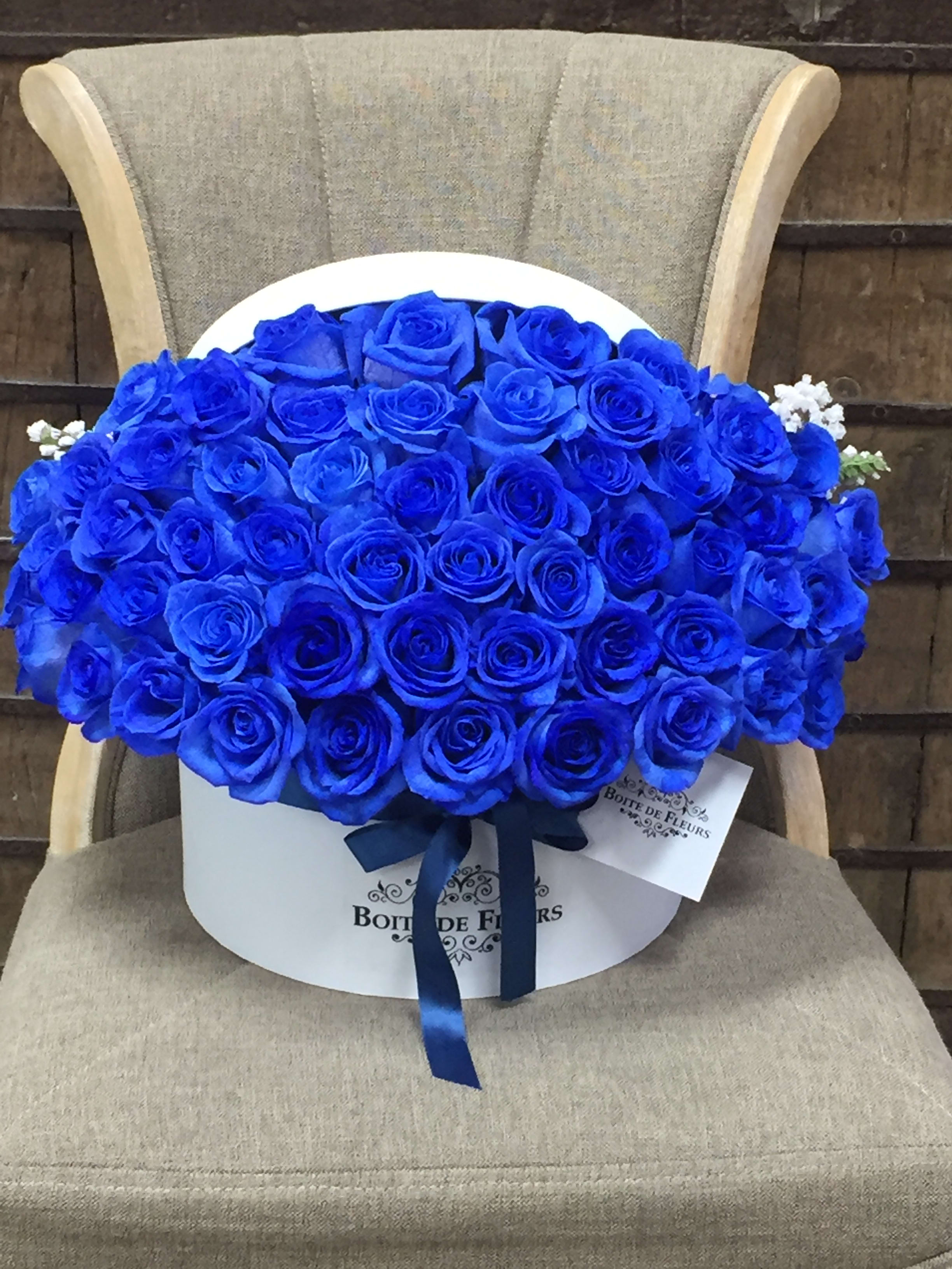 Large bouquet of vivid blue roses in a white hat box with ribbon