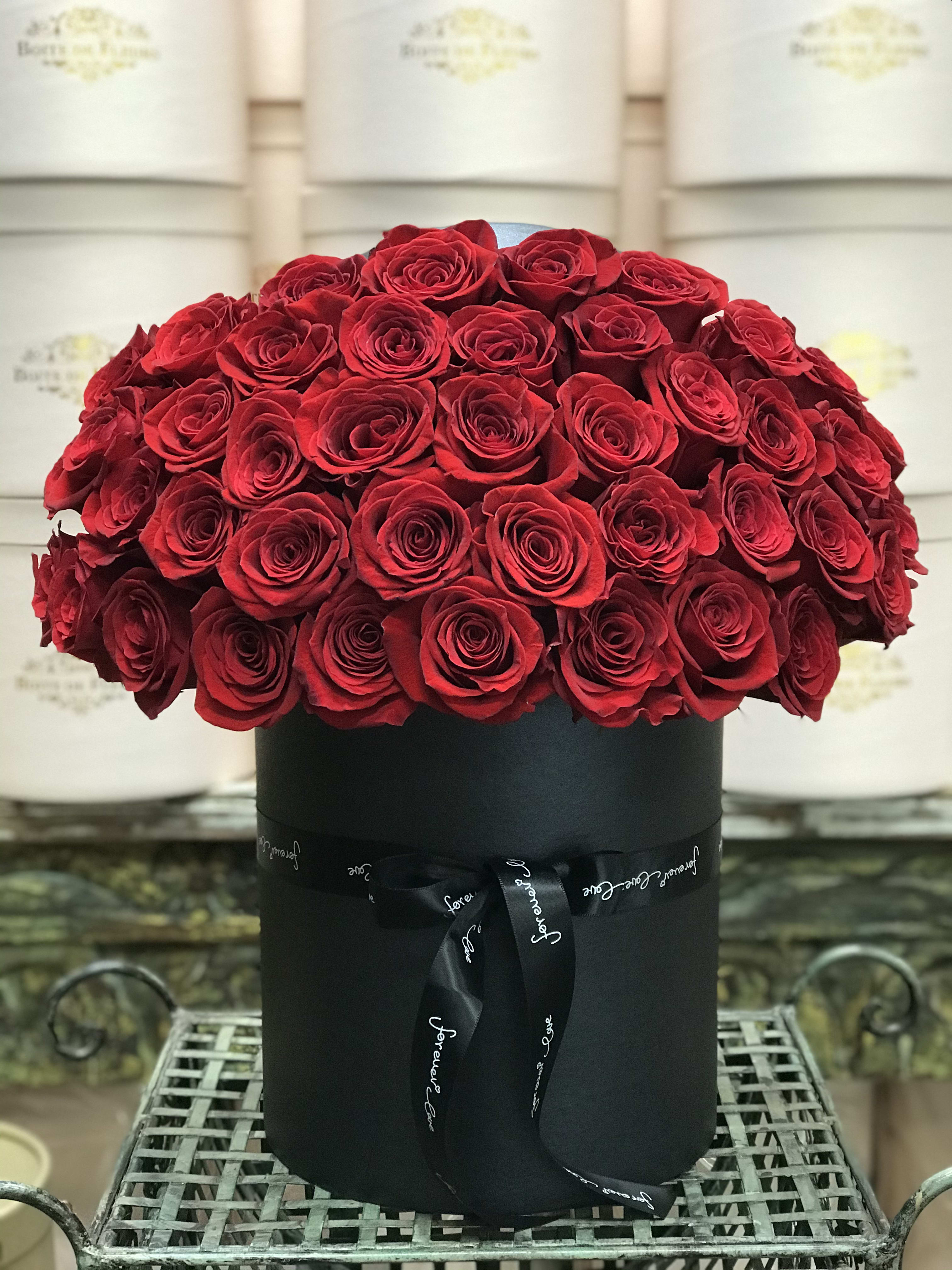 Red roses arranged in a black round box with a ribbon