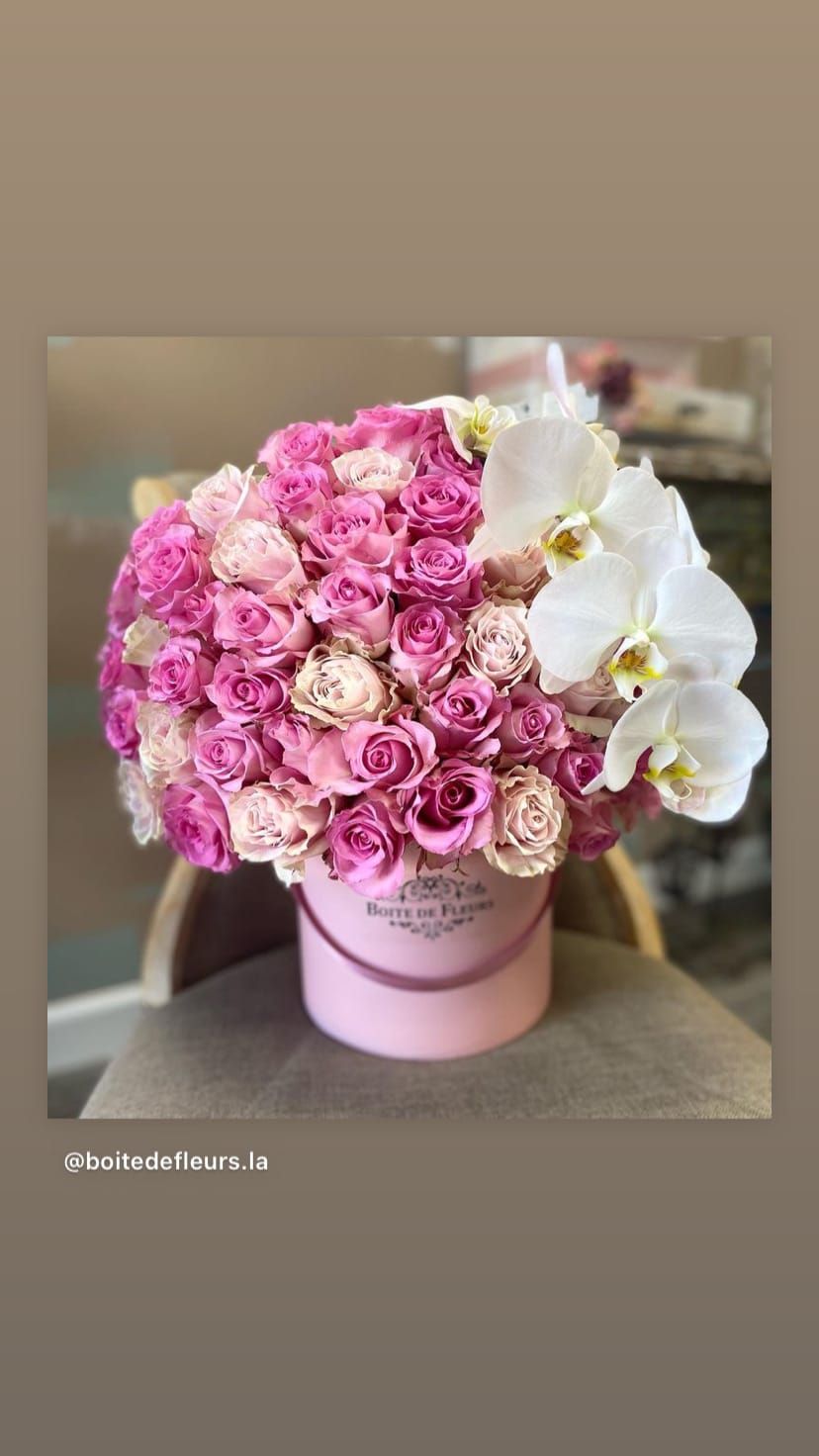 Pink roses and white orchids arranged in a pink hat box