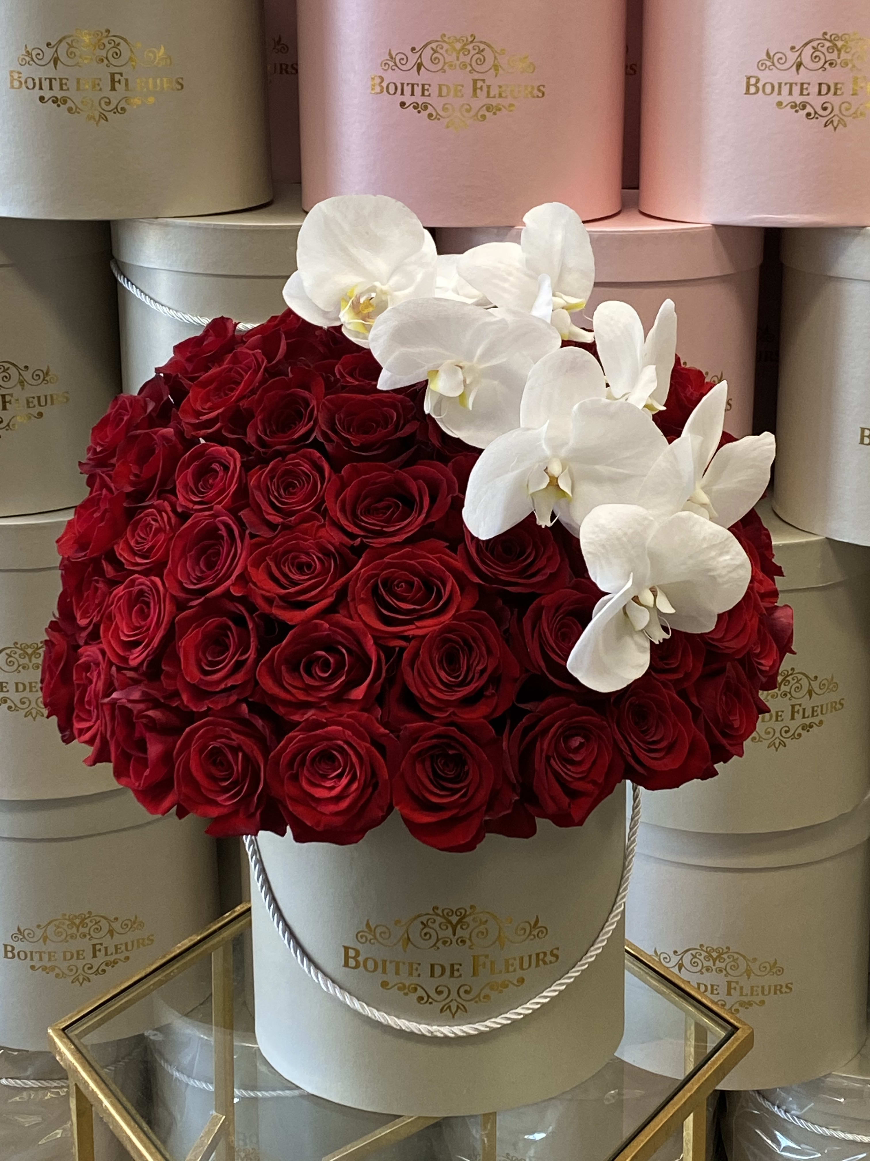 Red roses with white orchids in a round hat box