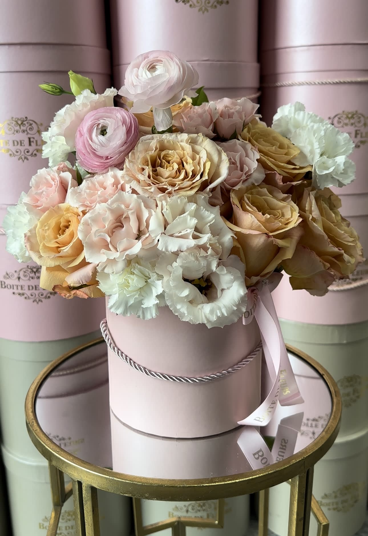 Pastel roses and carnations arranged in a pink hat box