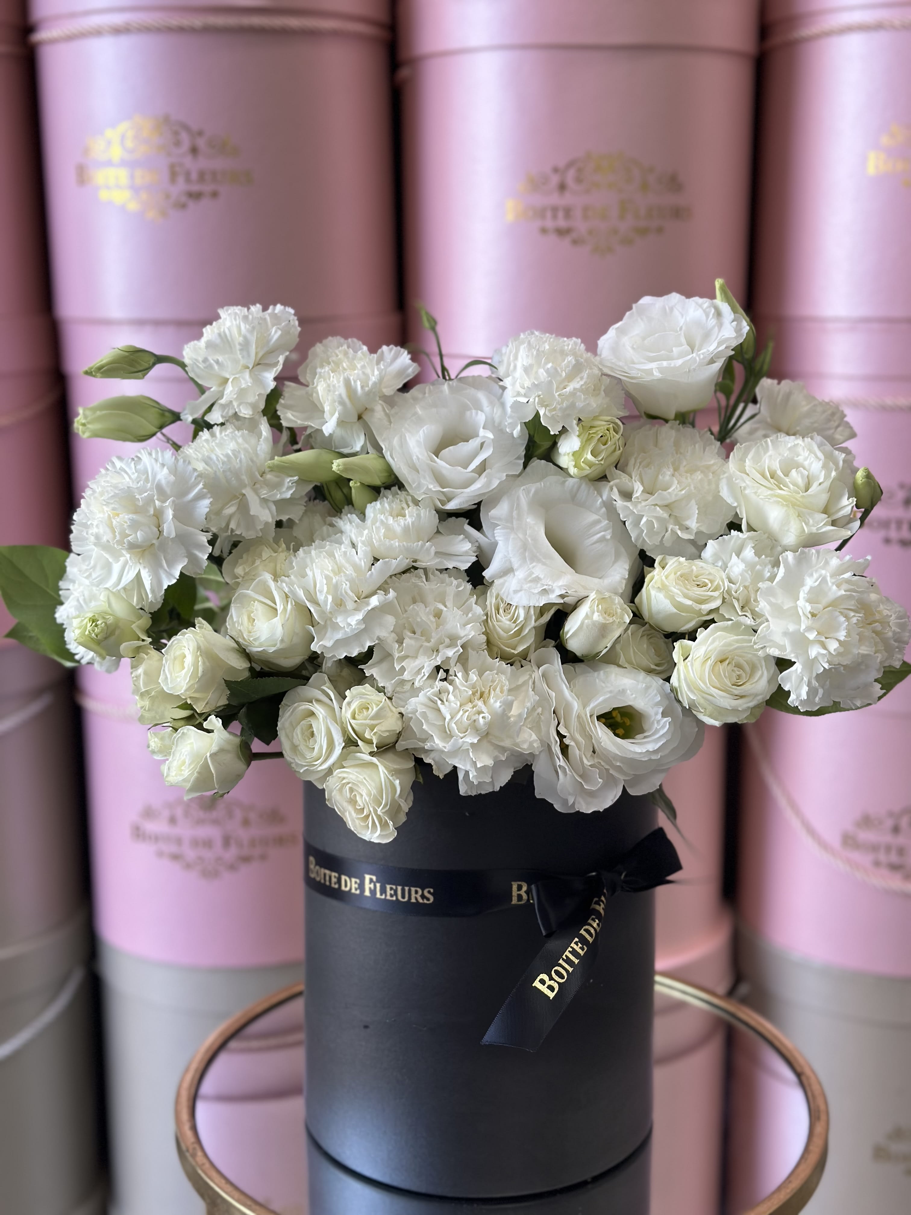 White roses and carnations arranged in a black hat box