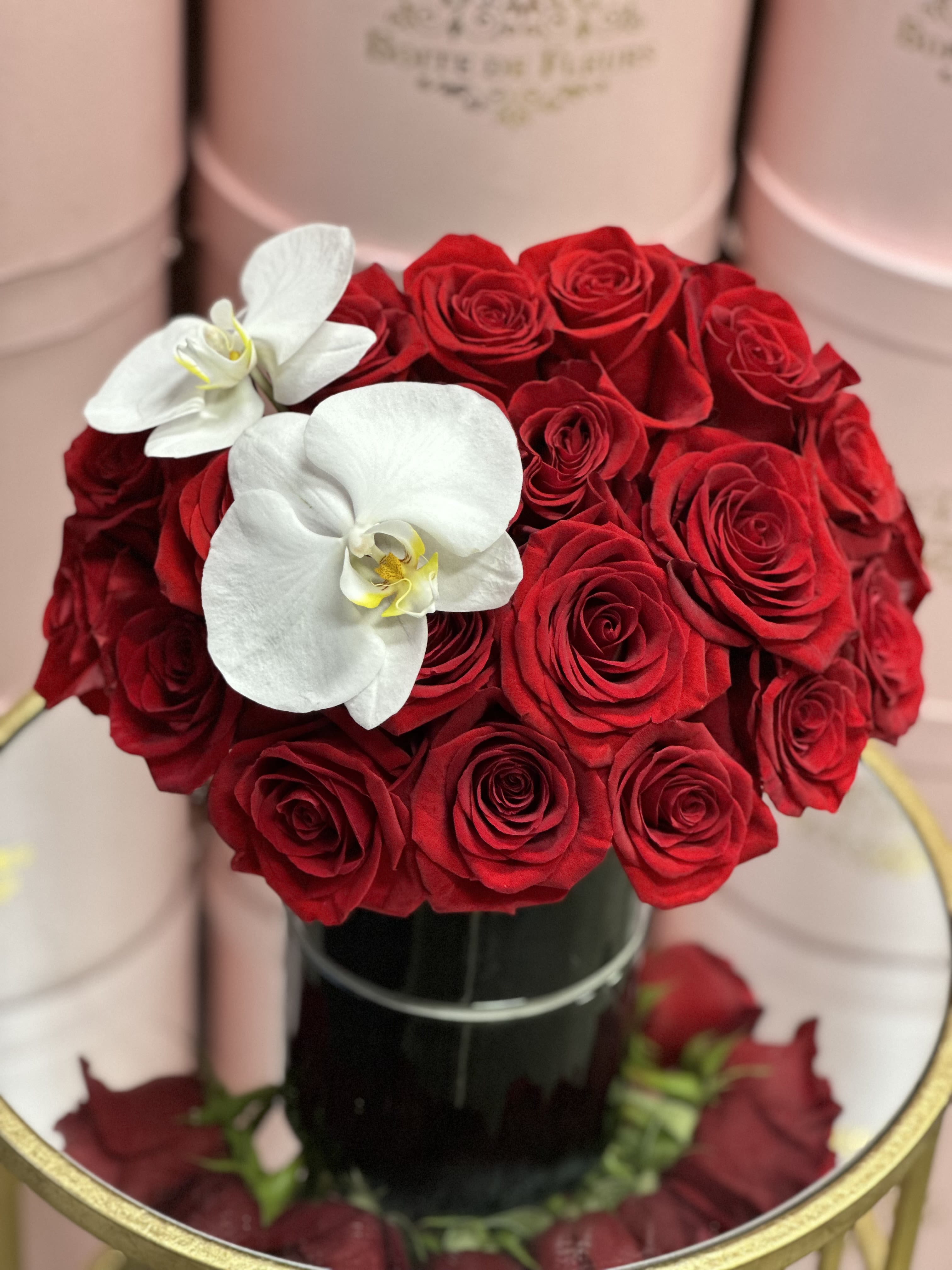 Red rose bouquet with two white orchids in a black vase