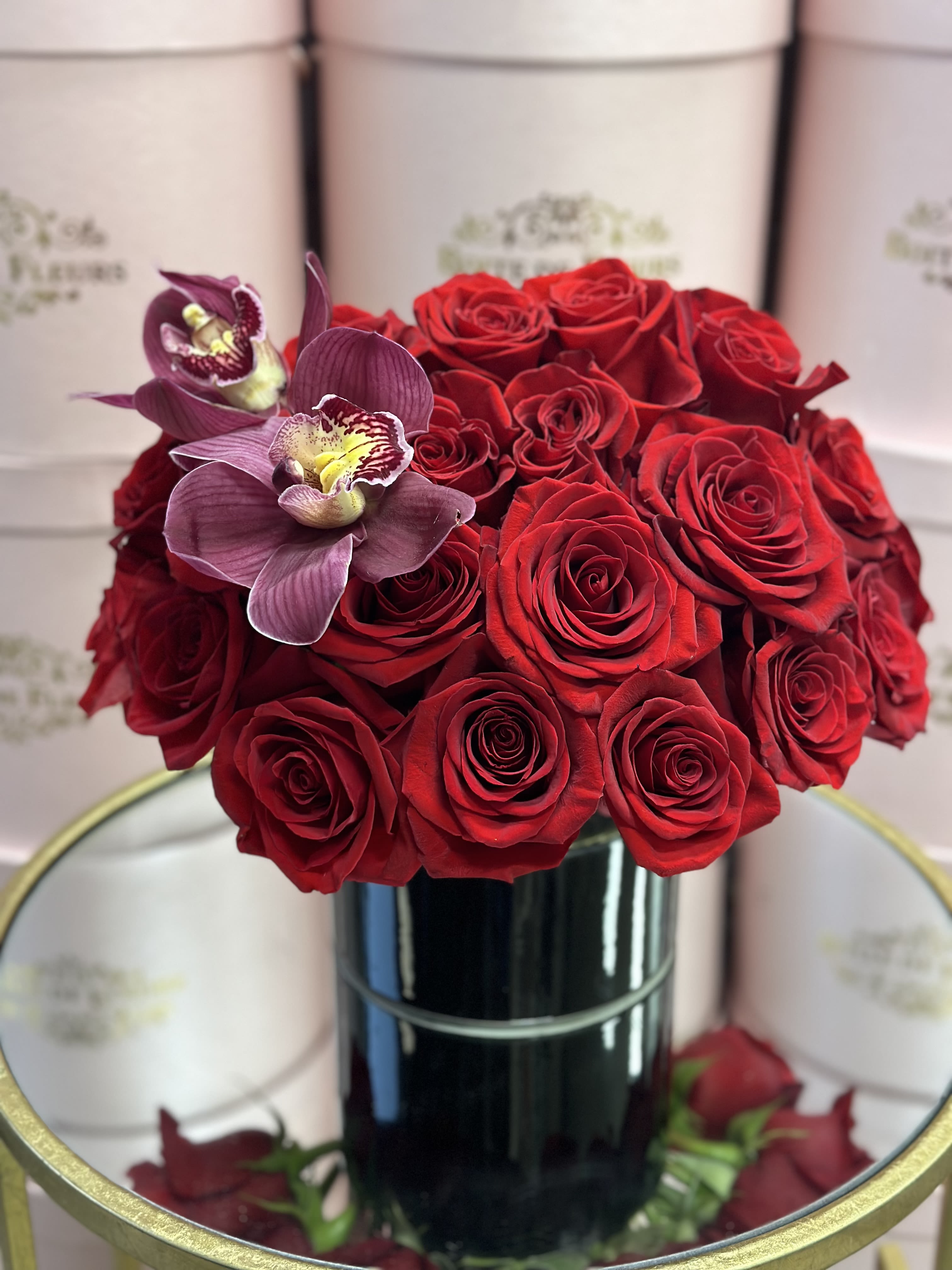 Red roses with two purple orchids in a black vase