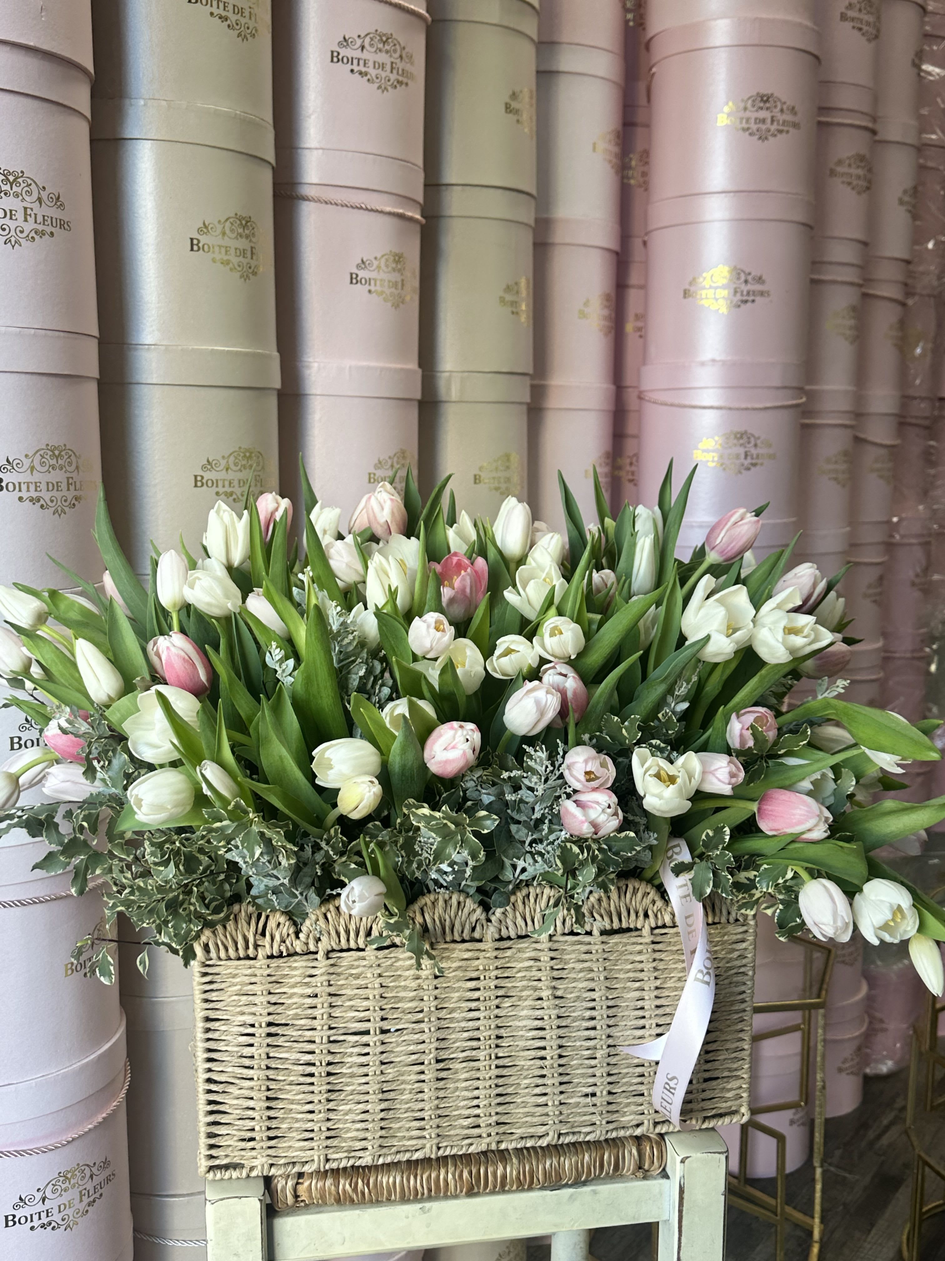 Basket arrangement of white and pink tulips with greenery