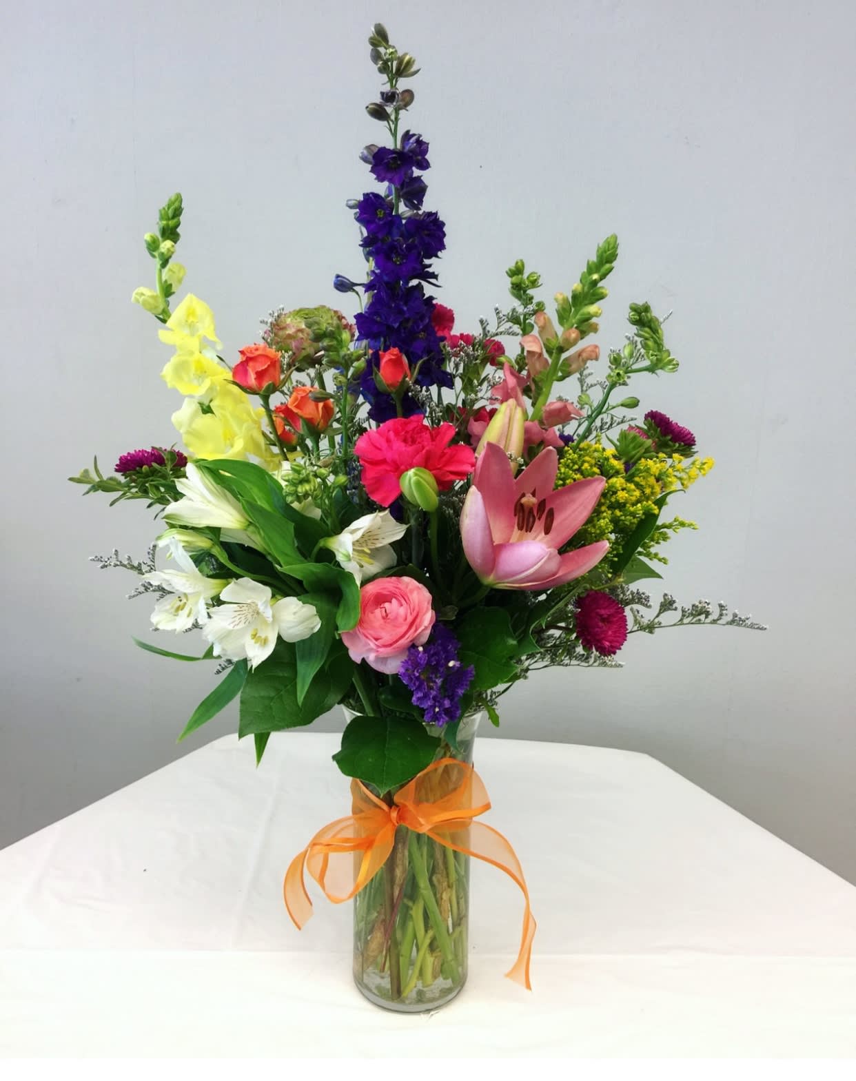 Colorful mixed bouquet in a glass vase with an orange ribbon