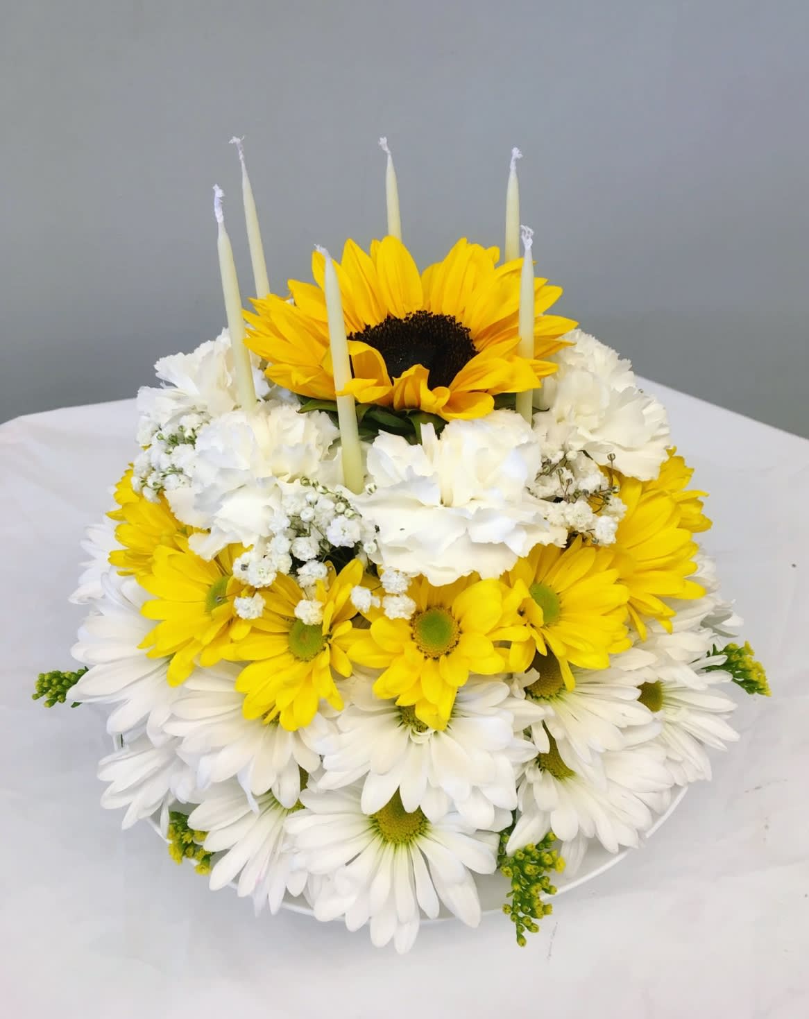 Tiered yellow and white flower cake with candles