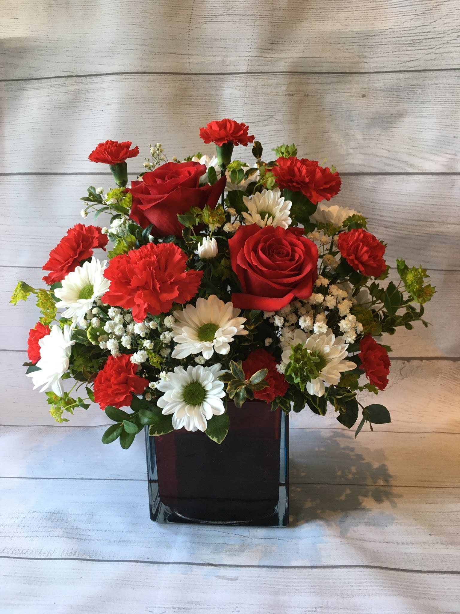 Red roses and white daisies in a black vase