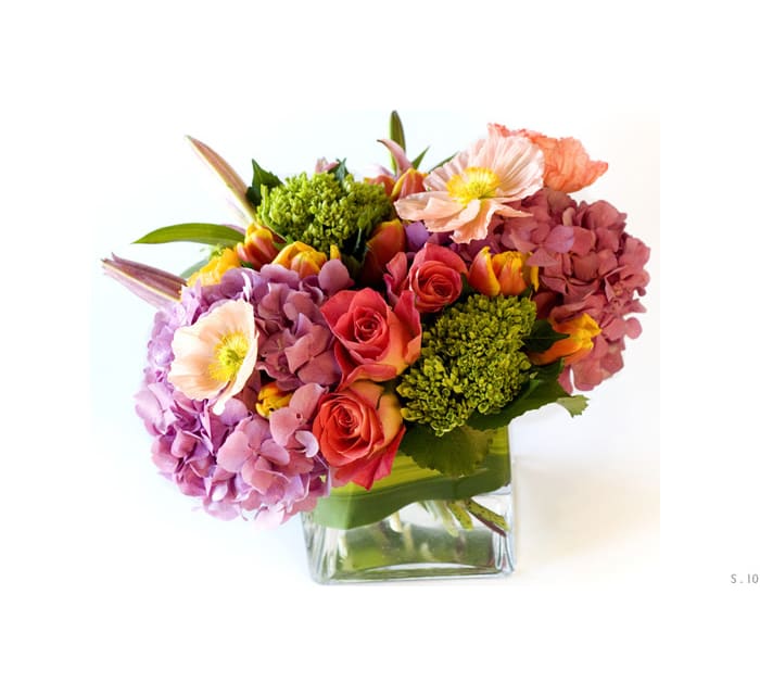 Mixed bouquet of pink and coral flowers in a clear glass vase