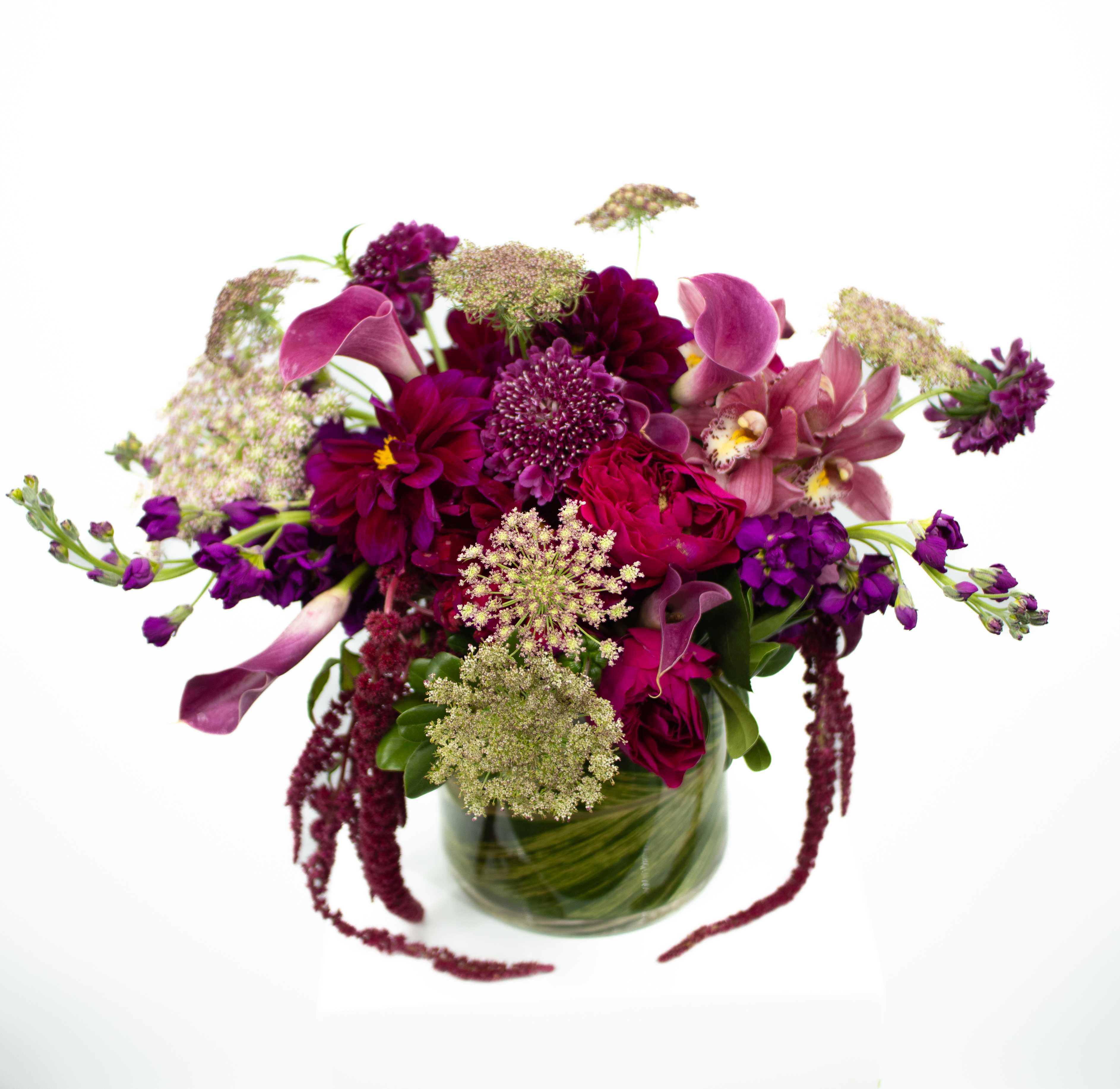 Bee Bee - An arrangement built to impress. This piece is made up of rich complementary colors with callas and orchids paired with cascading floral elements. This is the prefect arrangement for some many occasions.