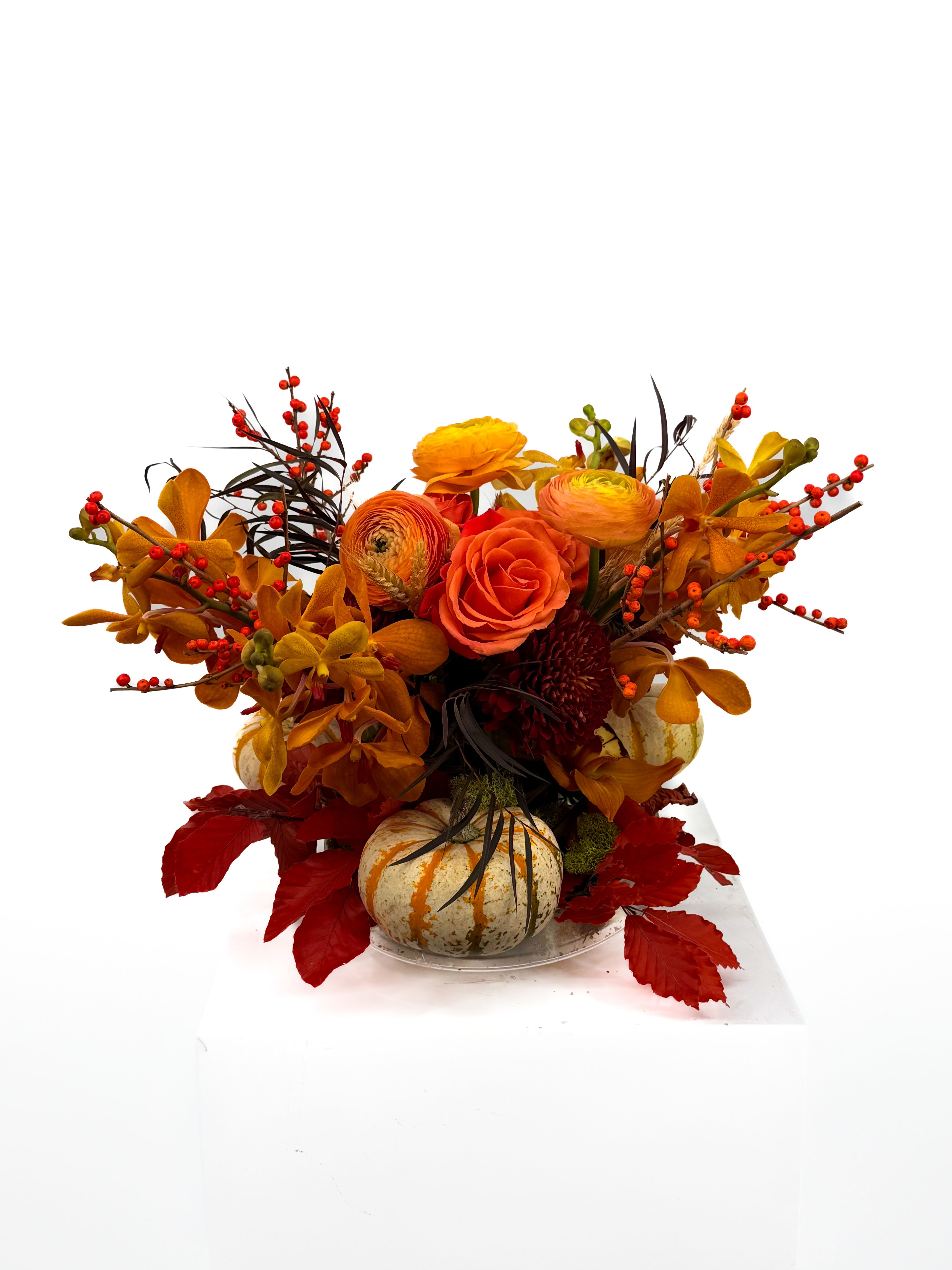 Ember - Ignite your fall décor with the Autumn Ember Bouquet, a radiant fusion of fiery oranges, deep reds, and golden tones. Nestled among vibrant seasonal blooms, miniature pumpkins and berry sprigs add a charming harvest touch. Designed to capture the warmth and glow of autumn’s embrace, this arrangement brings cozy sophistication to any table, entryway, or festive celebration.  -Perfect for Thanksgiving gatherings, fall weddings, or as a statement piece to welcome the season home.