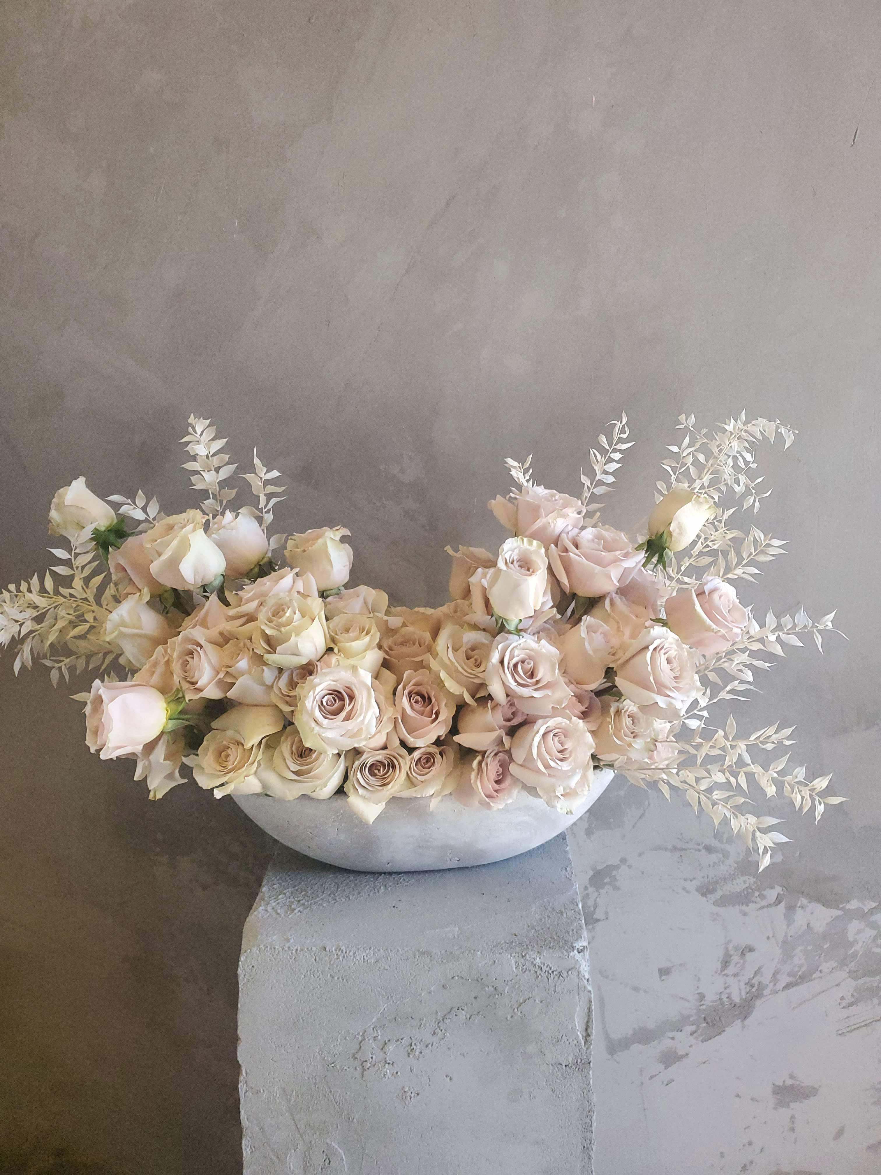 Simple Yet Loud - A modern, clean design with Nude Roses, in a modern oval concrete shape vase with Preserved fillers