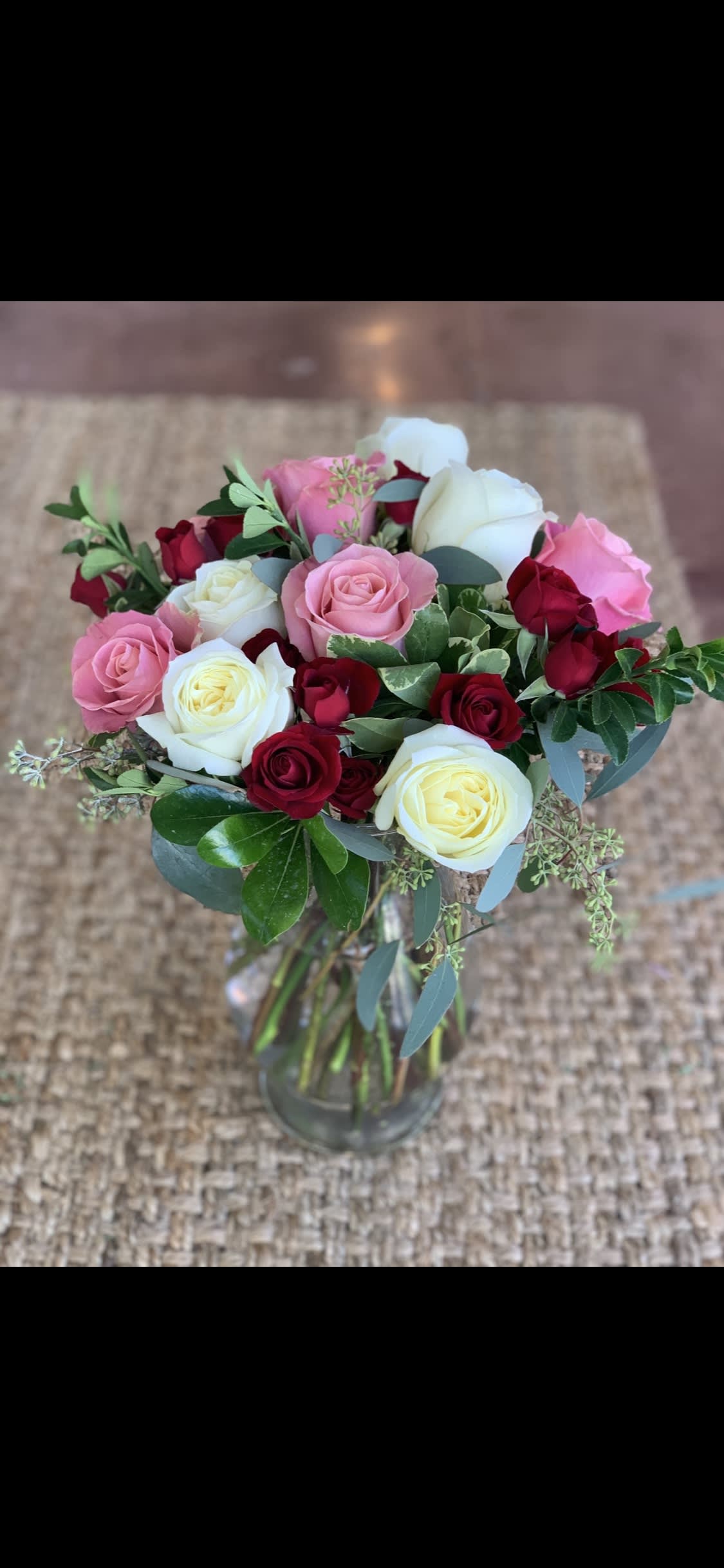 Bouquet of pink, white, and red roses in a glass vase