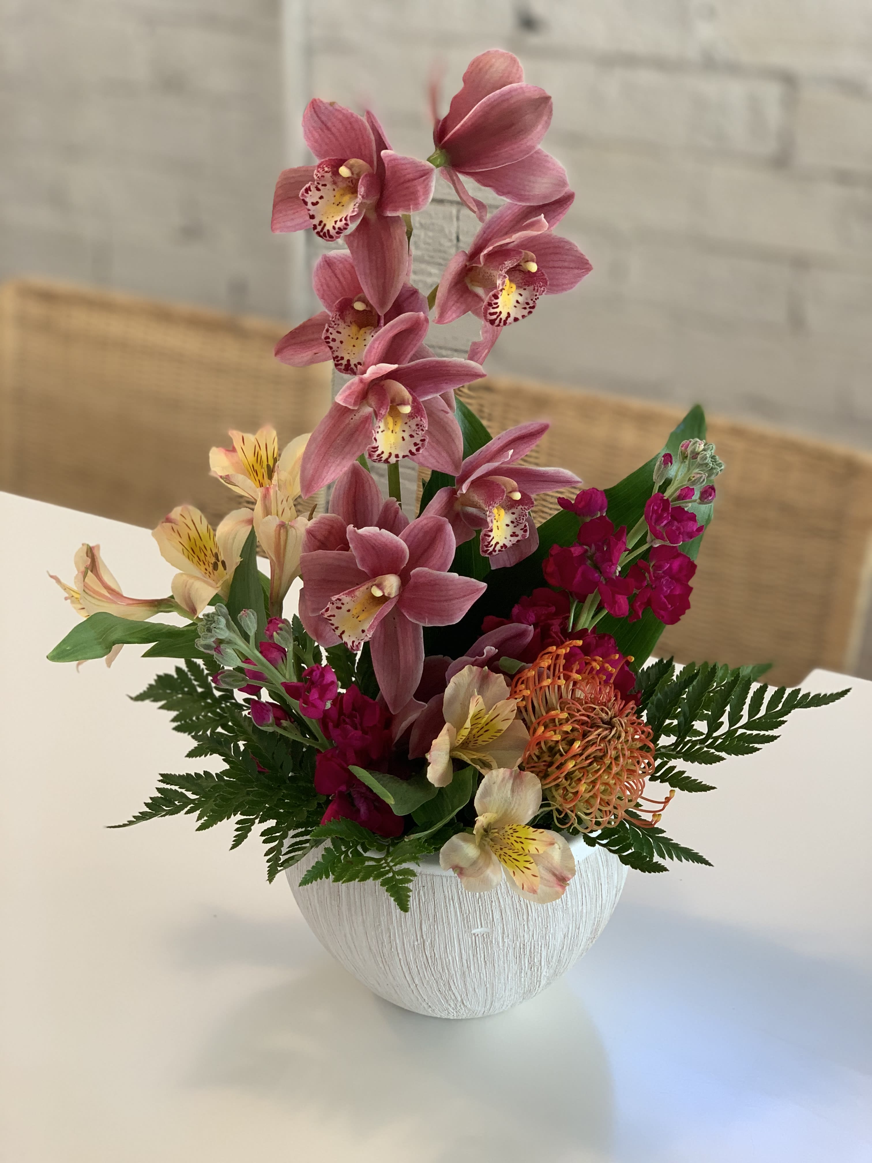 Pink orchid arrangement in a white textured vase