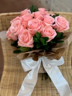 Bouquet of pink roses wrapped with brown paper and a white ribbon