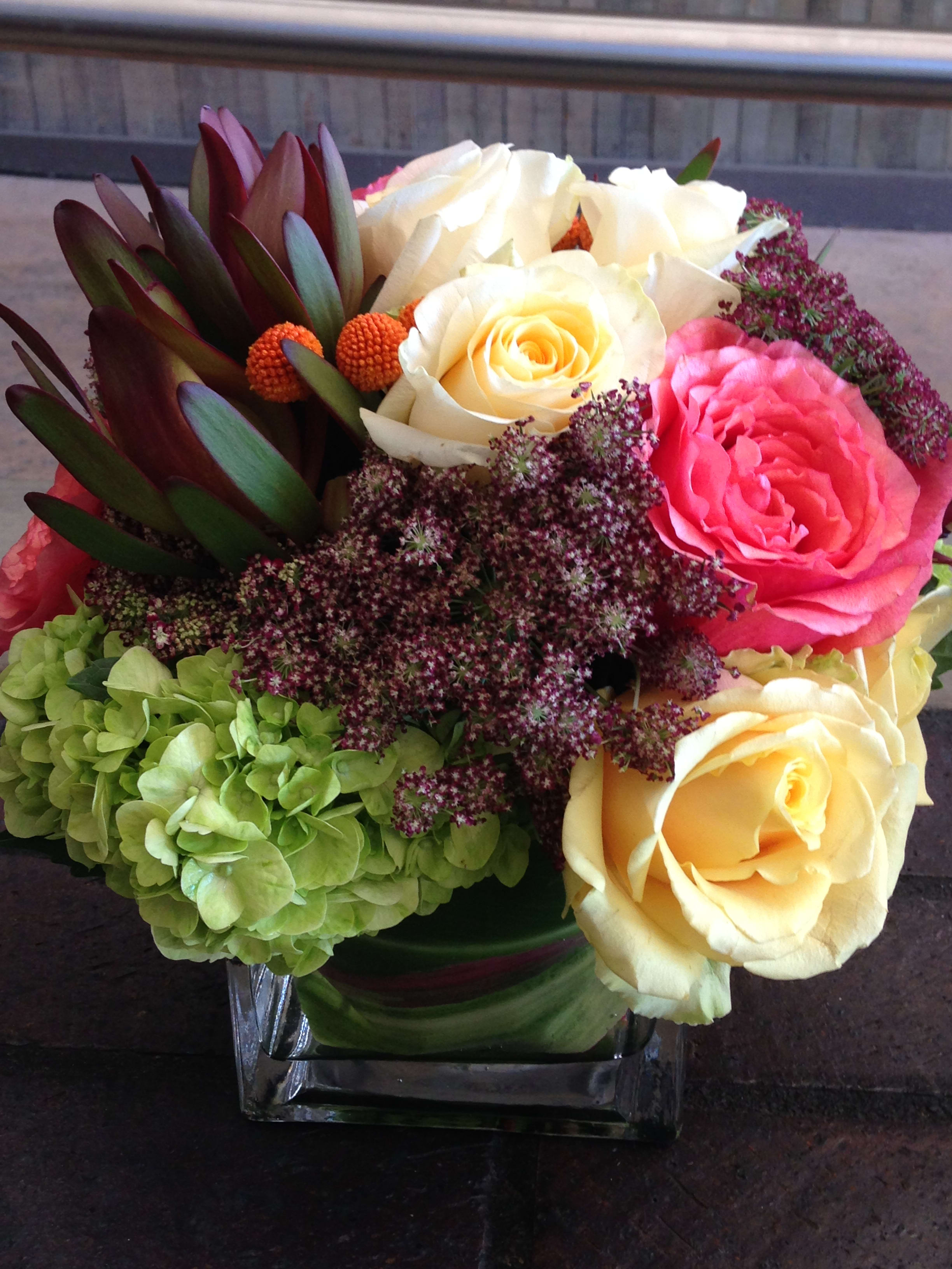 Bouquet of cream and pink roses with green hydrangea in a glass vase