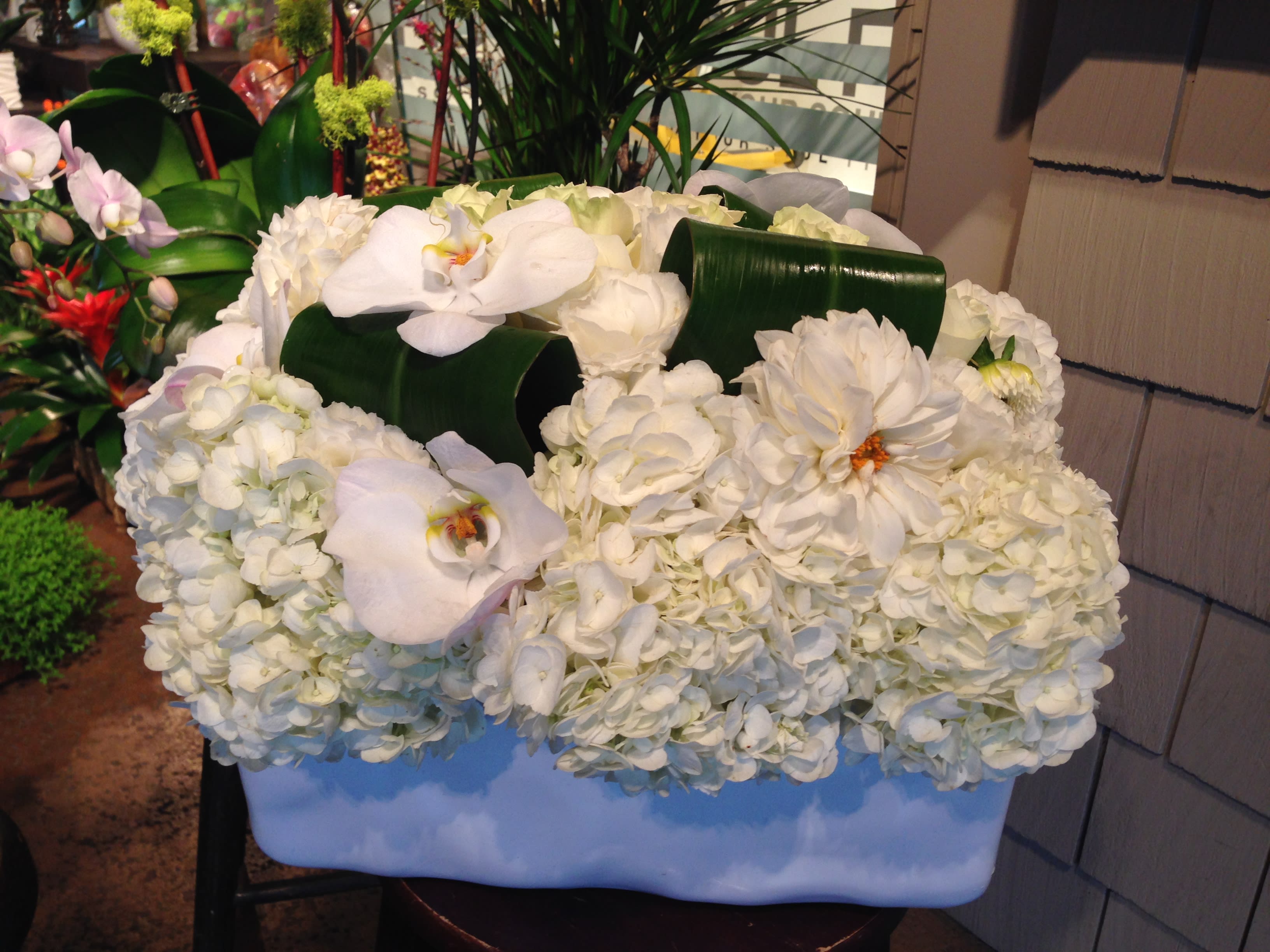White floral arrangement with orchids and hydrangeas in a rectangular container