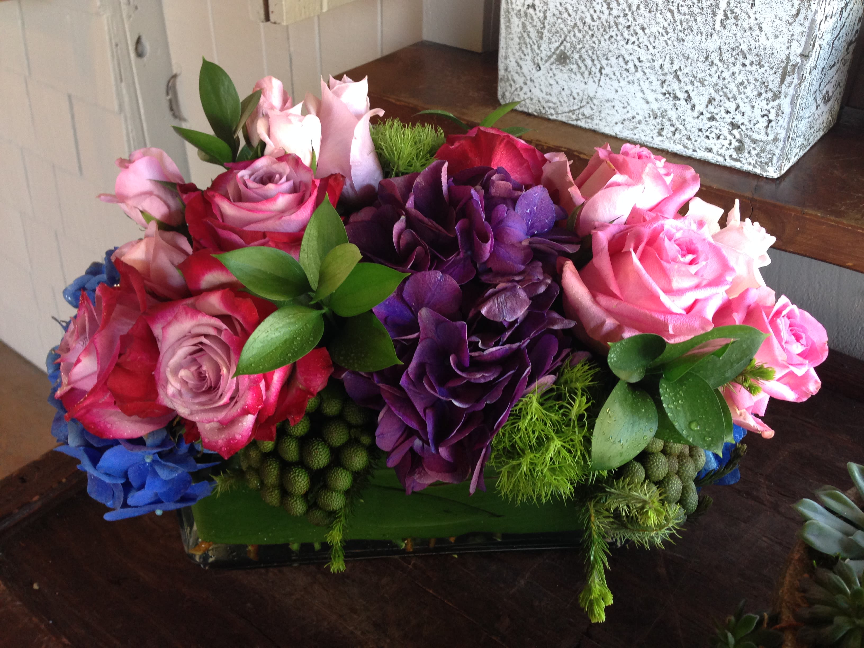 Pink and purple rose arrangement in a low rectangular vase