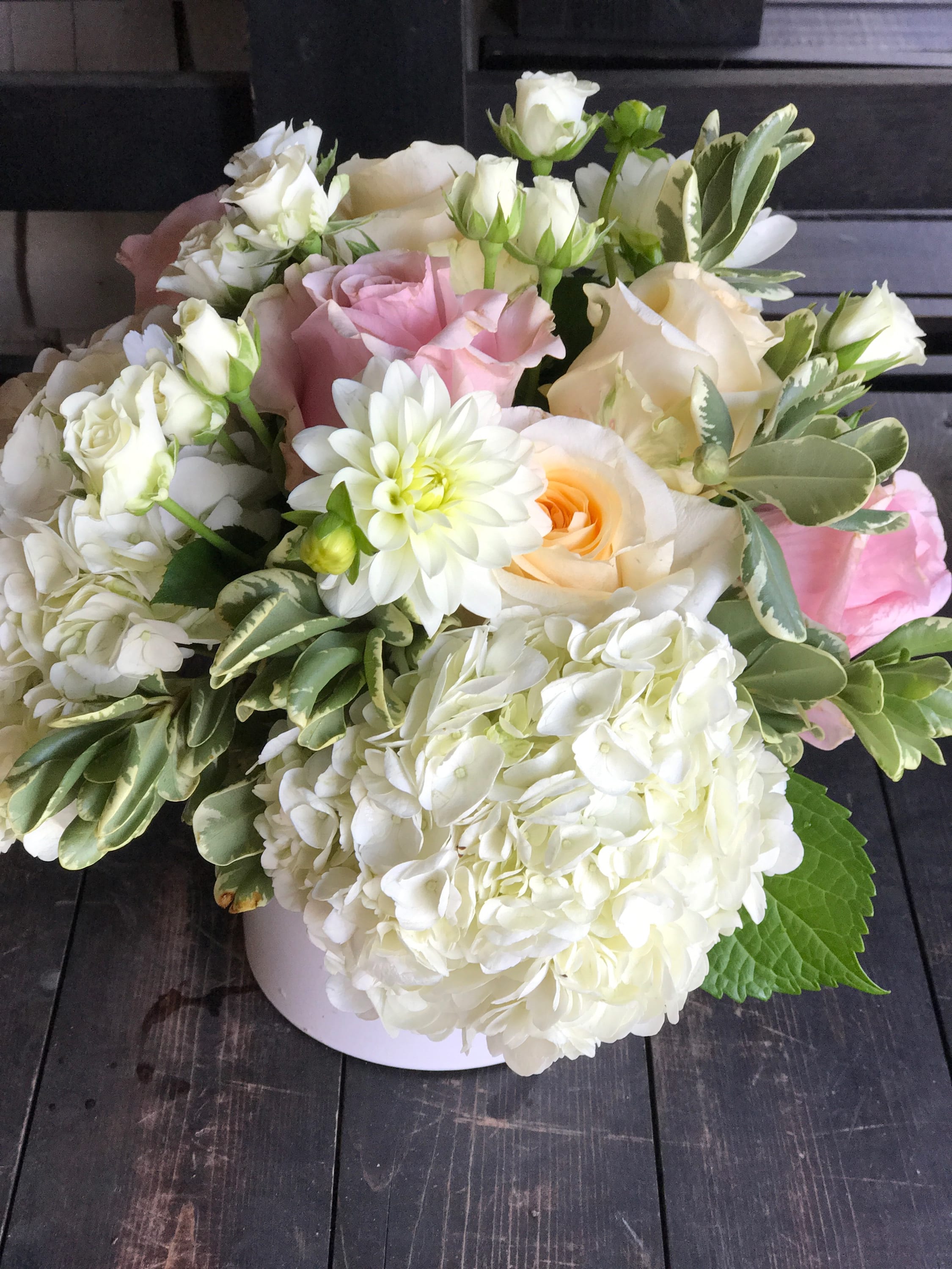 Bouquet of white and blush roses with white hydrangeas in a white vase