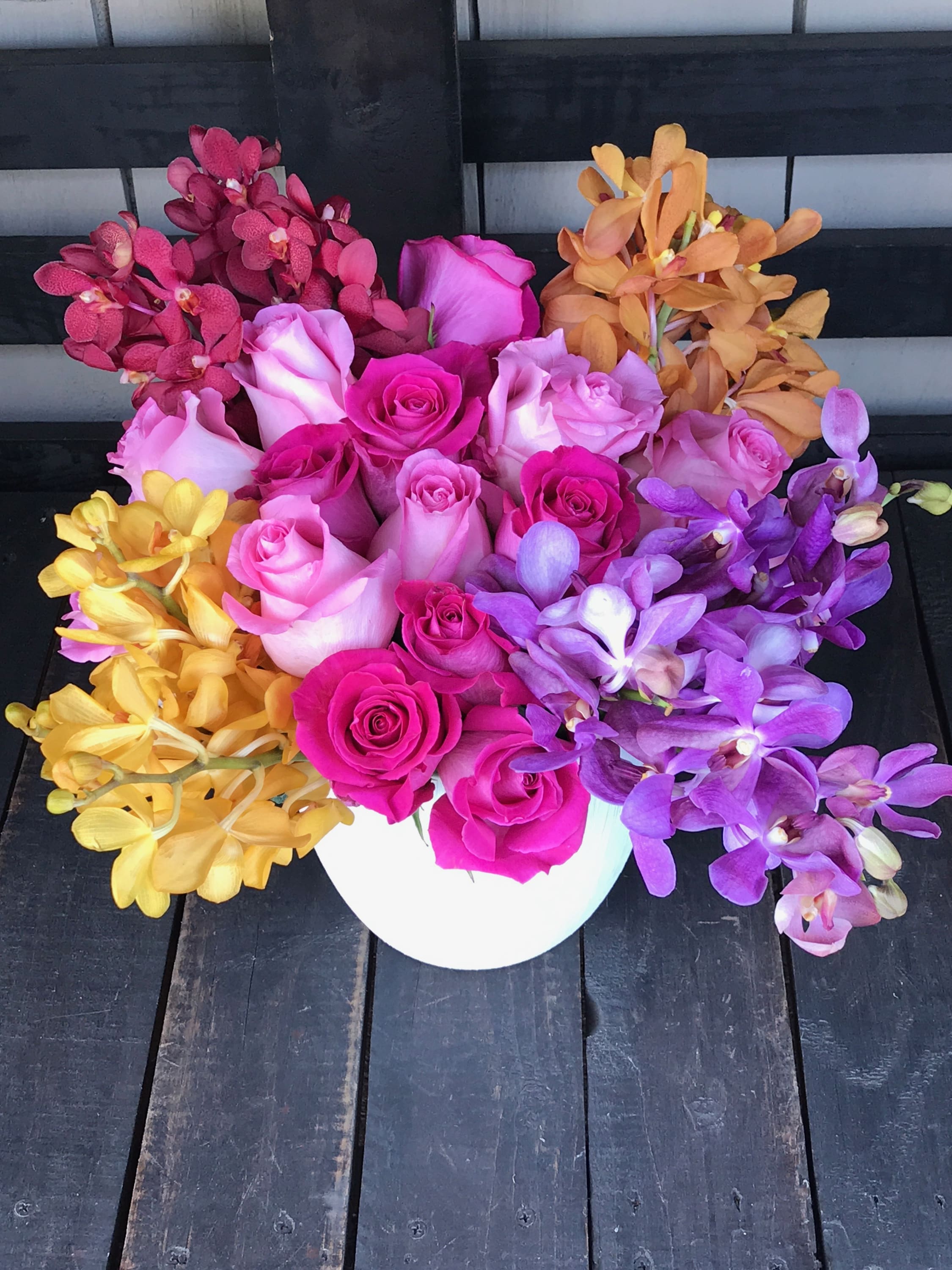 Colorful bouquet of roses and orchids in a white vase