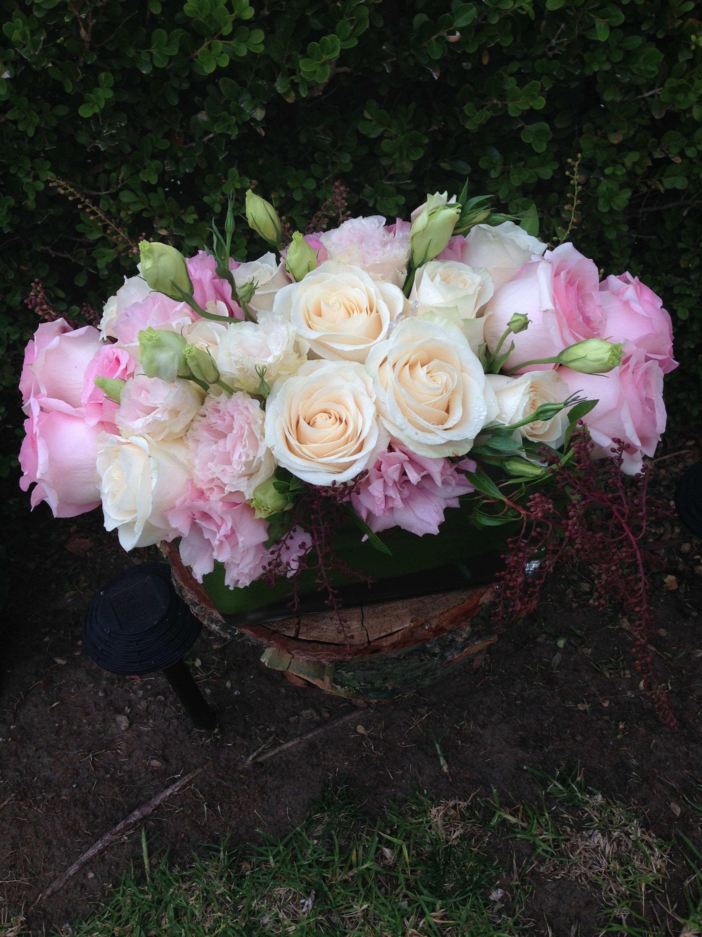 Pink and white rose bouquet with pale blooms in a low container