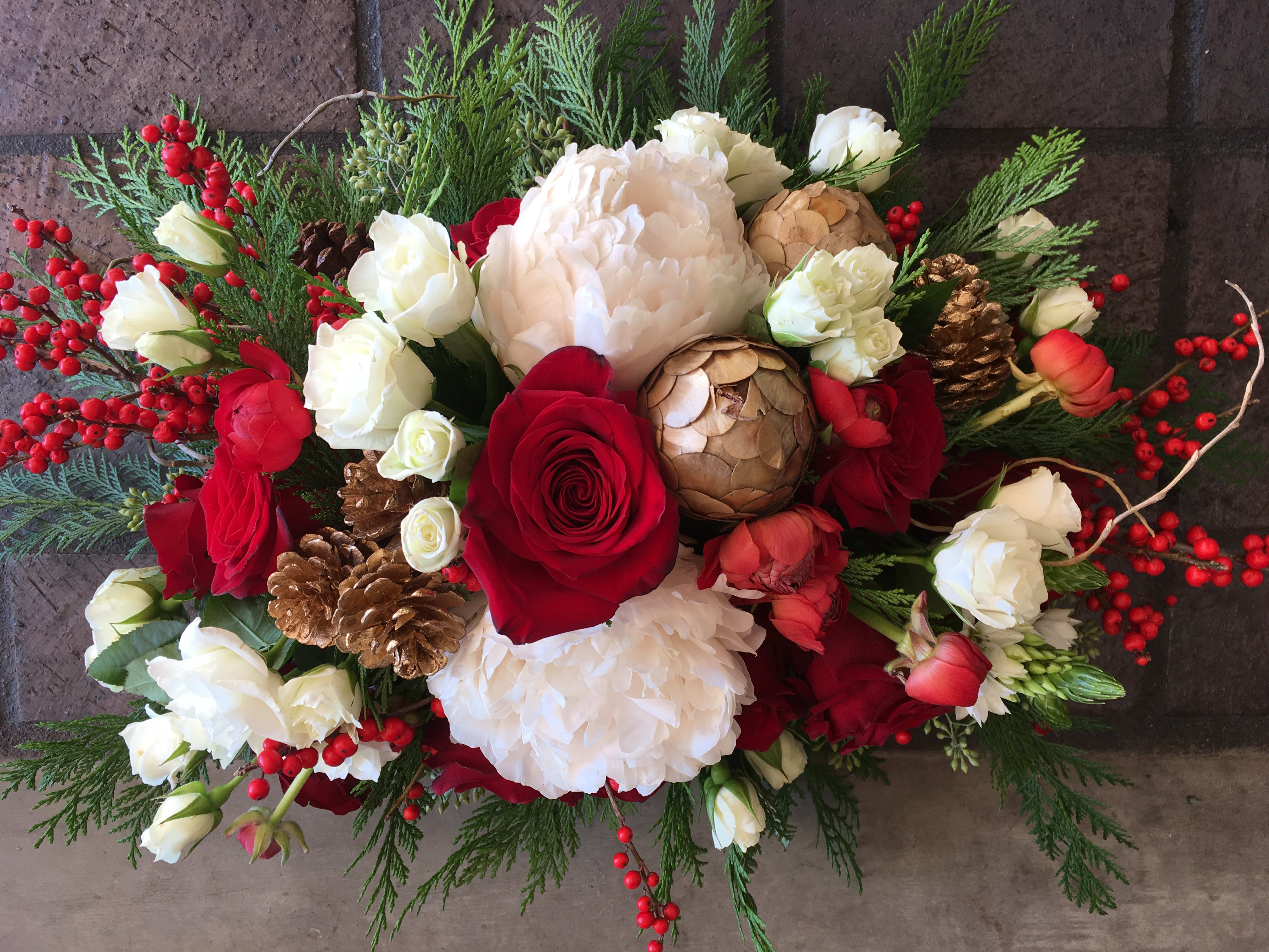 Red and white floral arrangement with pinecones and berries
