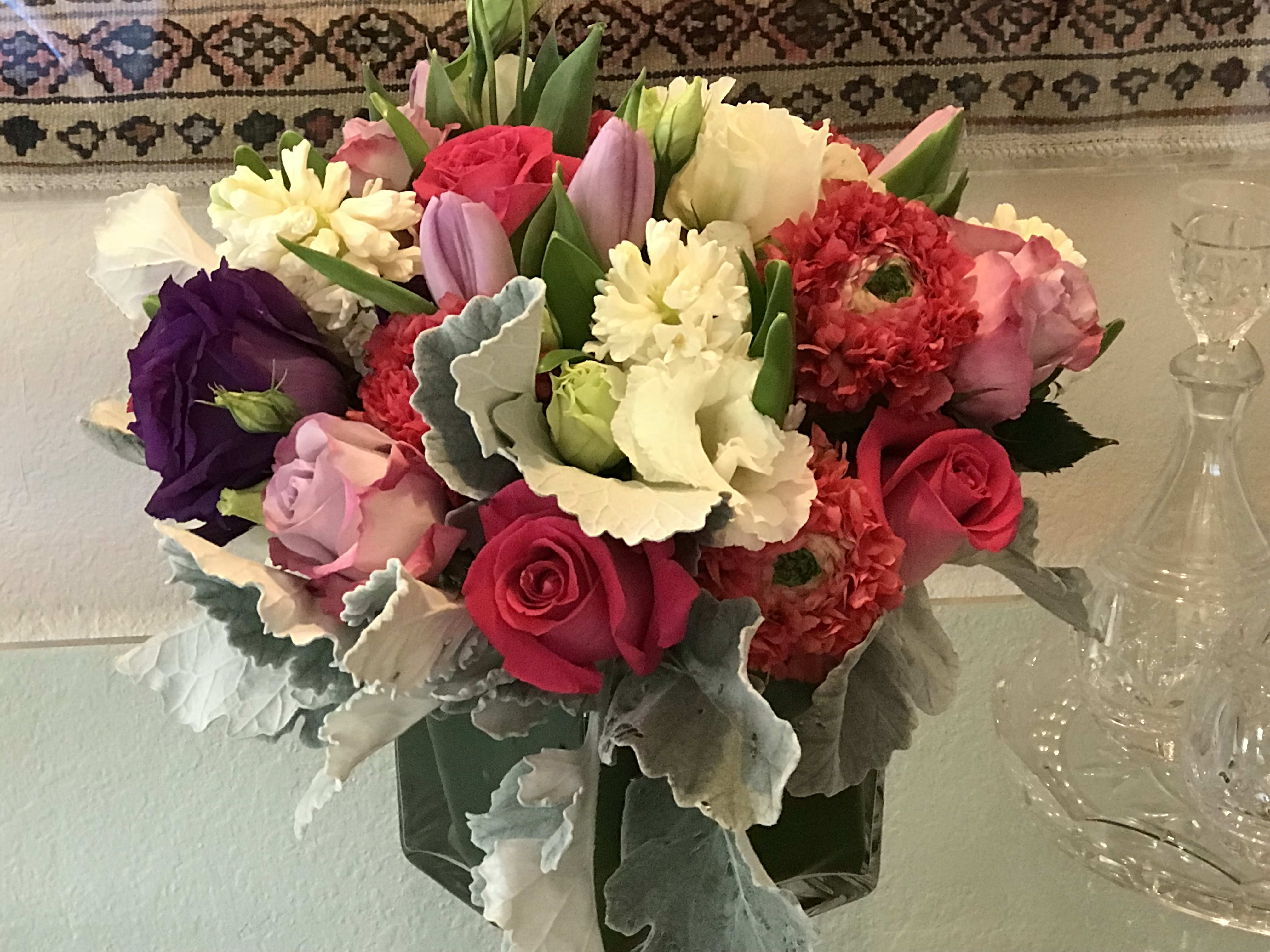 Mixed bouquet of roses, tulips, and carnations in a glass vase