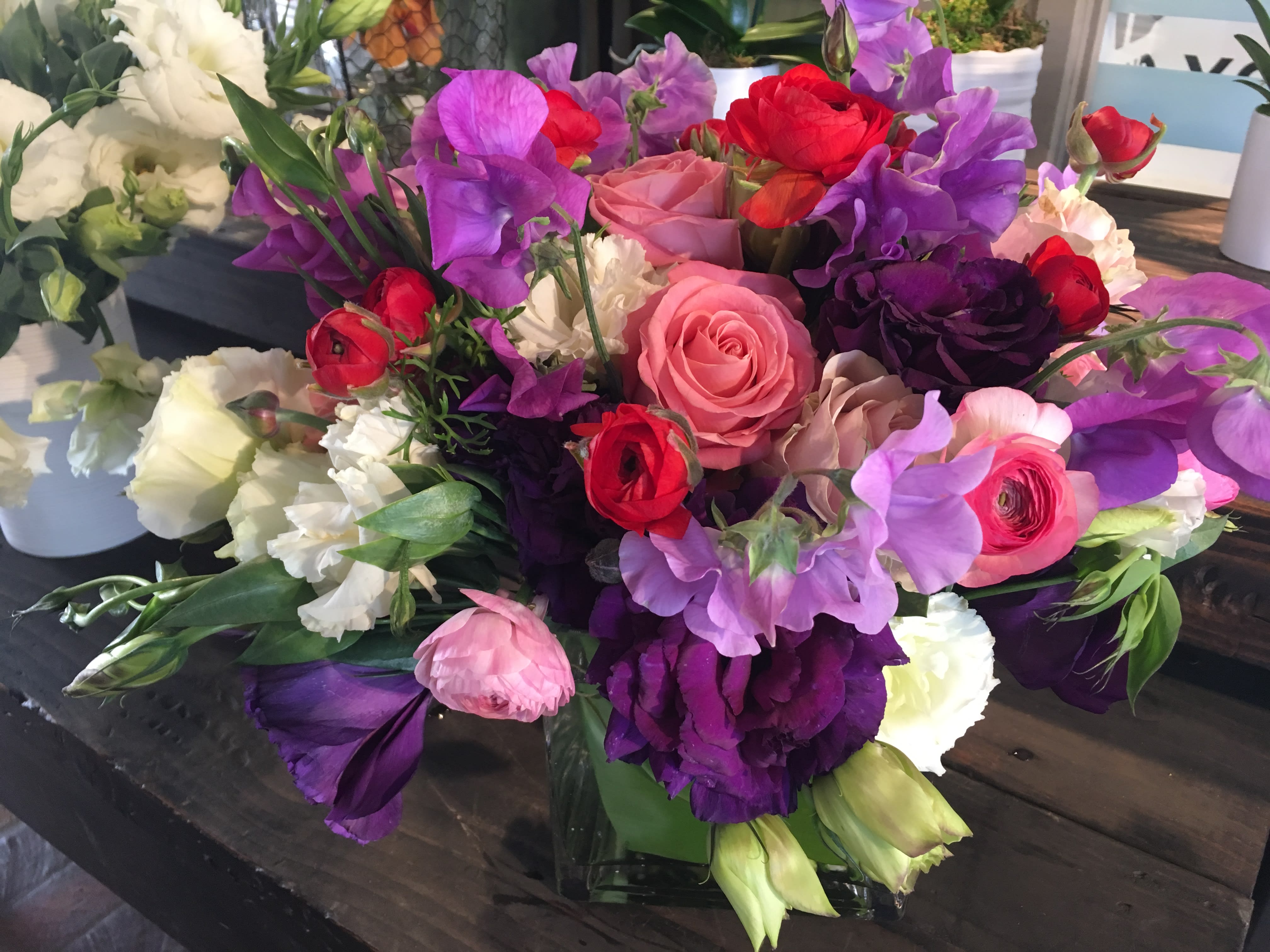 Mixed bouquet of pink, purple, red, and white flowers in a low vase