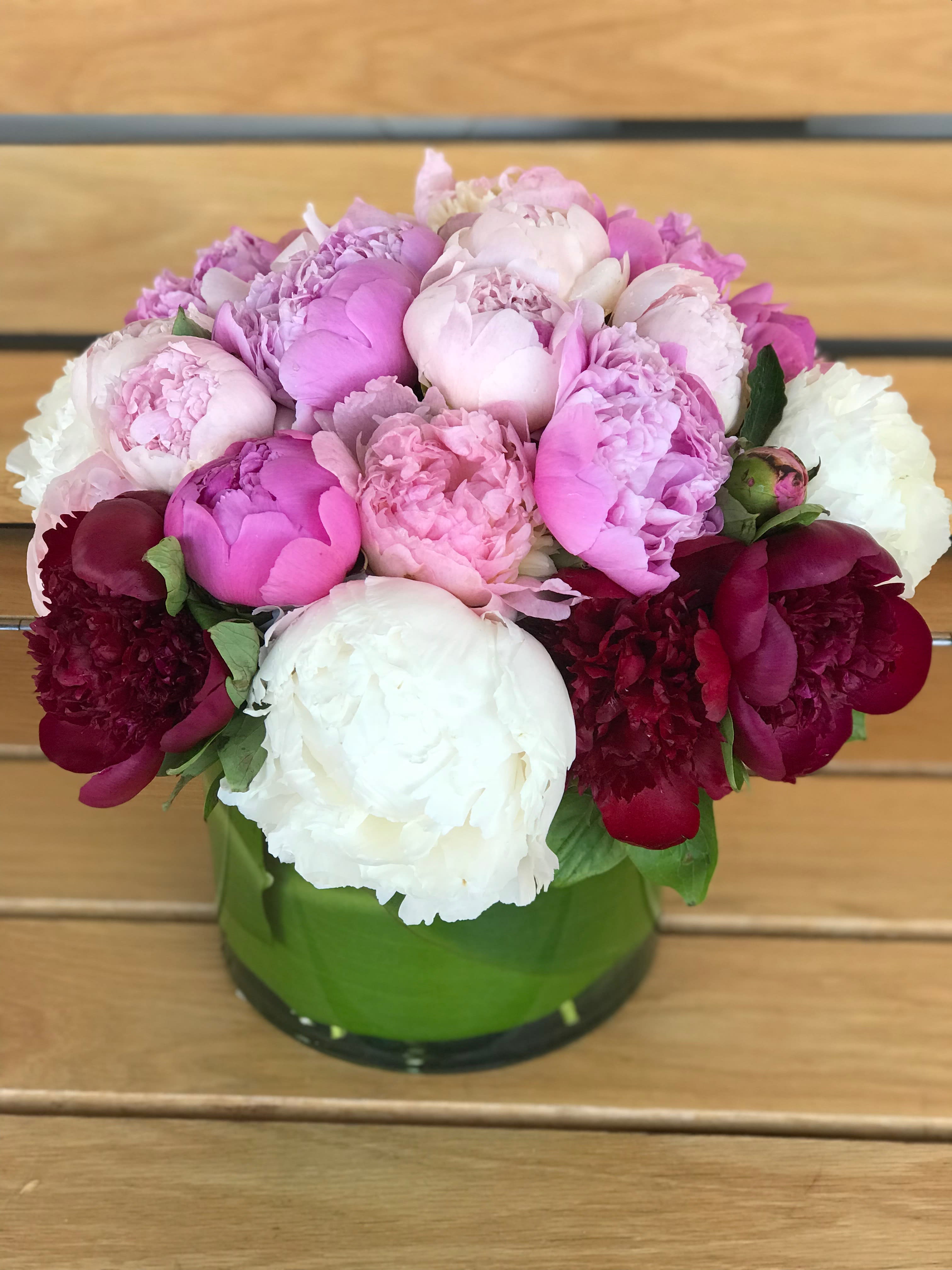 Pink and white peonies arranged in a green glass vase