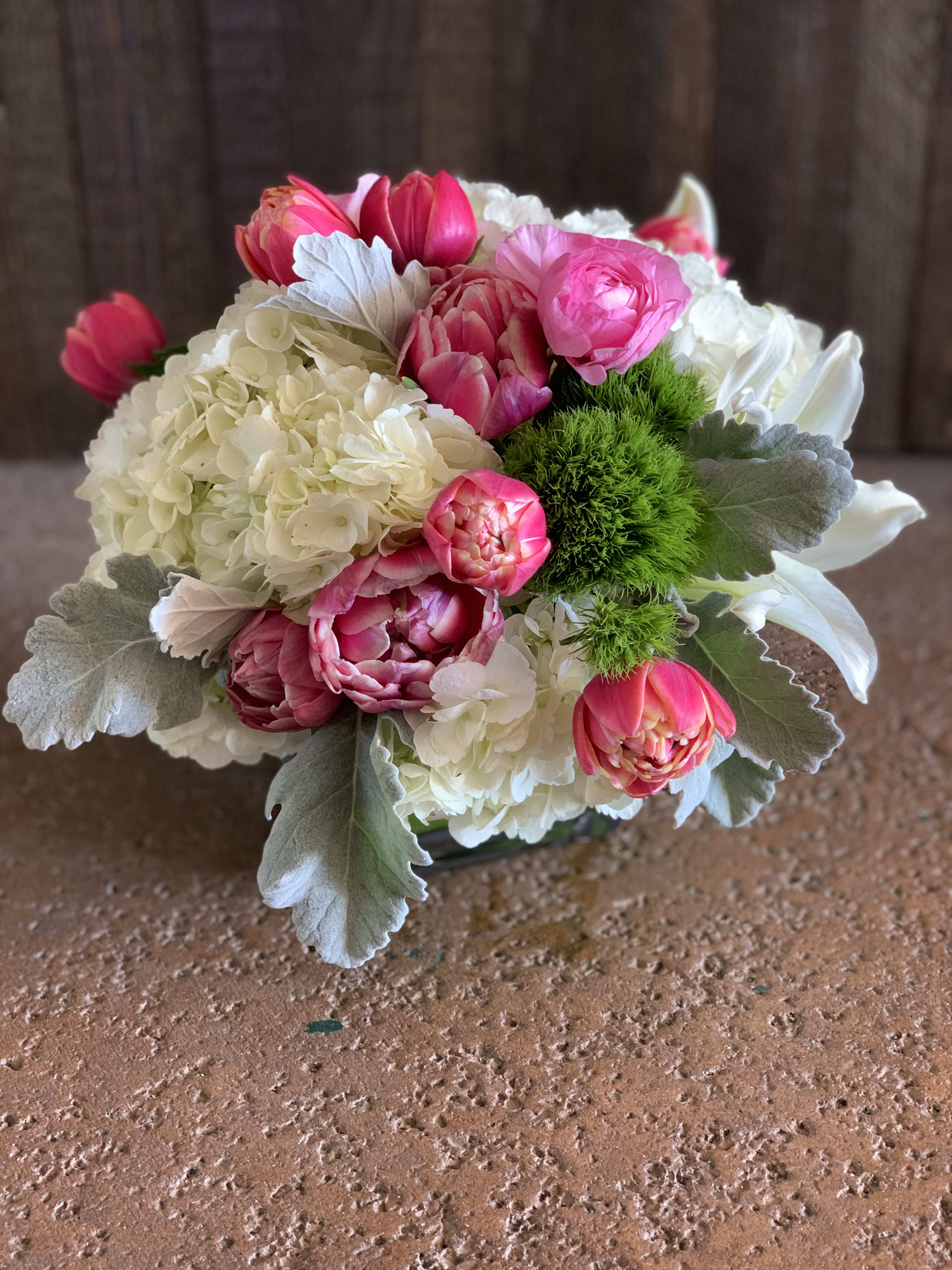 Pink tulips and white hydrangeas in a low bouquet with silver foliage