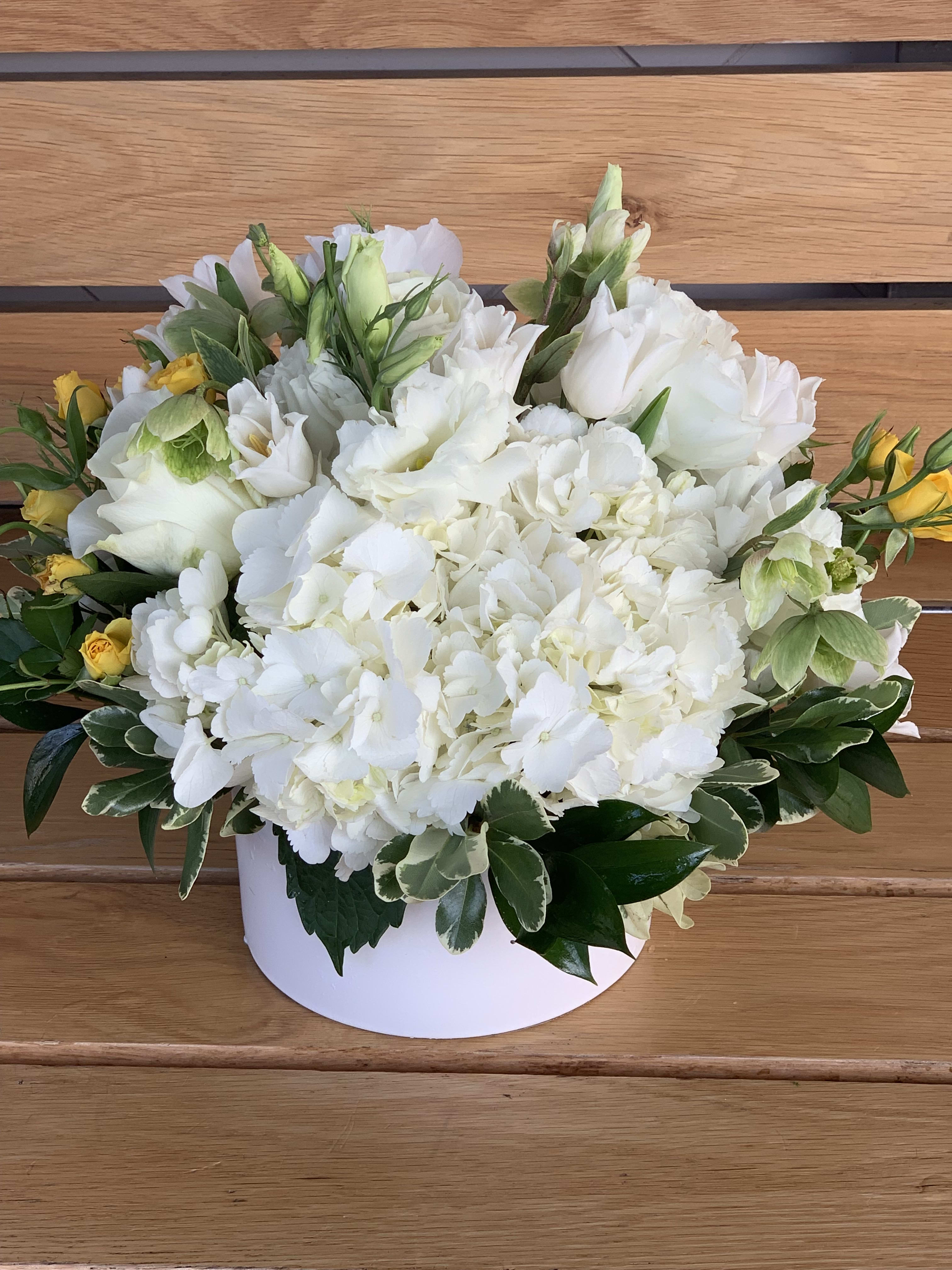 White hydrangea arrangement with yellow spray roses in a white box